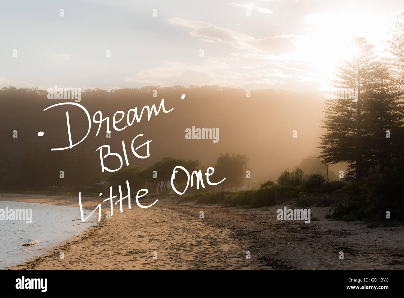 Dream Big Little One message. Handwritten motivational text over sunset calm sunny beach background with vintage filter applied Stock Photo
