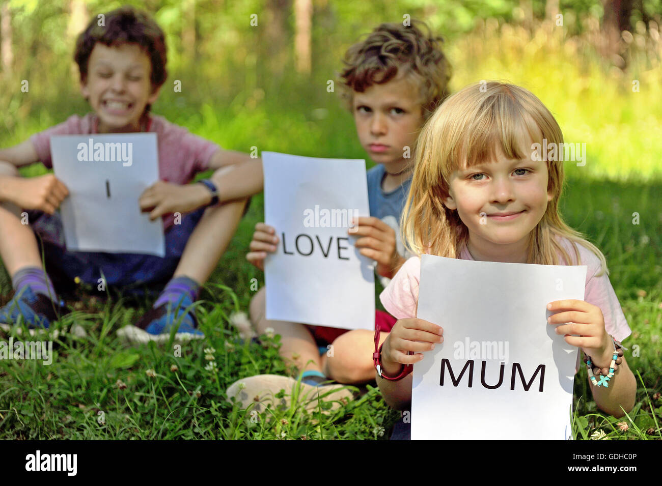Three kids with the sign I love mum Stock Photo