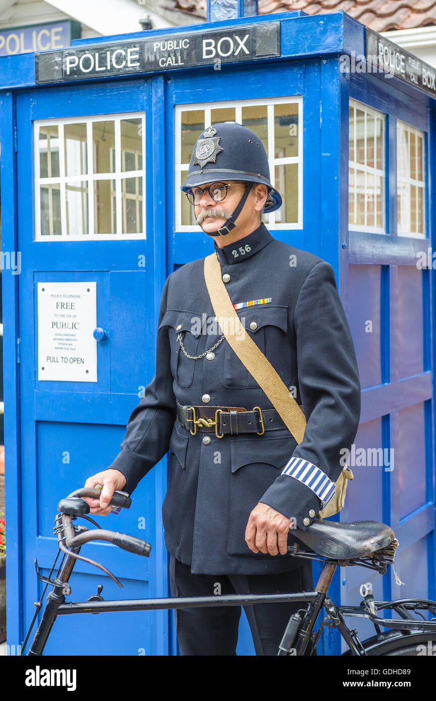 Woodhall Spa 1940s Festival - Policeman dressed in 1940s uniform stood by a traditional police telephone box Stock Photo