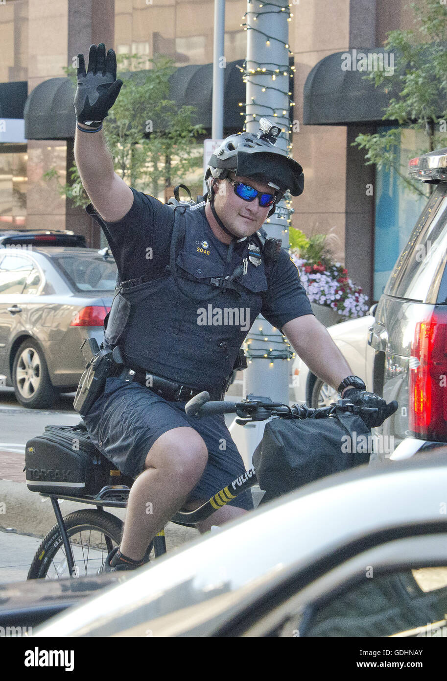 Cleveland, Ohio, USA. 16th July, 2016. A police officer on a bicycle acknowledges the applause of bystanders as he and his colleagues ride down Euclid Avenue about two blocks from the Quicken Loans Arena, site of the 2016 Republican National Convention in Cleveland, Ohio on Saturday, July 16, 2016.Credit: Ron Sachs/CNP. © Ron Sachs/CNP/ZUMA Wire/Alamy Live News Stock Photo