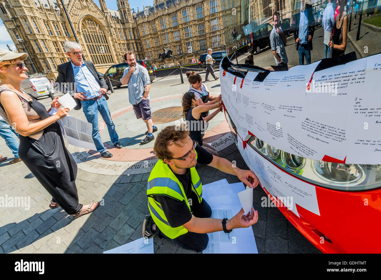 London, UK. 18th July, 2016. John Sauven, executive director of Greenpeace UK, watches as the front of the bus is covered in messages -  The Brexit ‘Vote Leave’ battle bus (used by Boris Johnson) has been acquired by Greenpeace was re-branded outside Parliament. The £350m NHS claim was covered with thousands of questions for the new government from Leave and Remain voters – many of them about what Brexit means for the environment. The questions, written on stickers, are forming a montage that will spell out the words ‘TIME FOR TRUTH’ in huge white letters on the side of the bus. The bus was pa Stock Photo