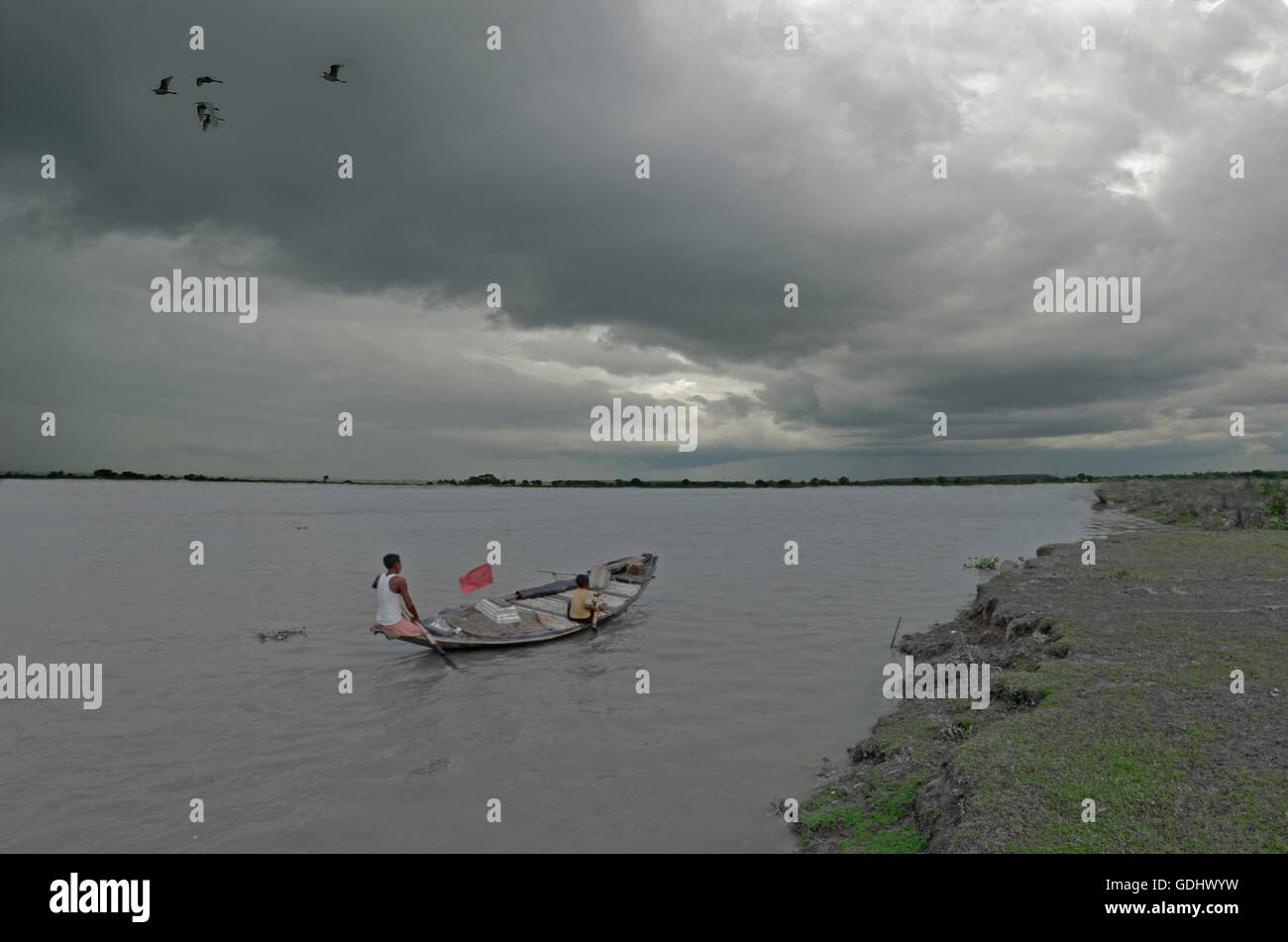 Fisherman and his son in his small dingy boat, out for fishing on a monsoon morning, West Bengal, India Stock Photo