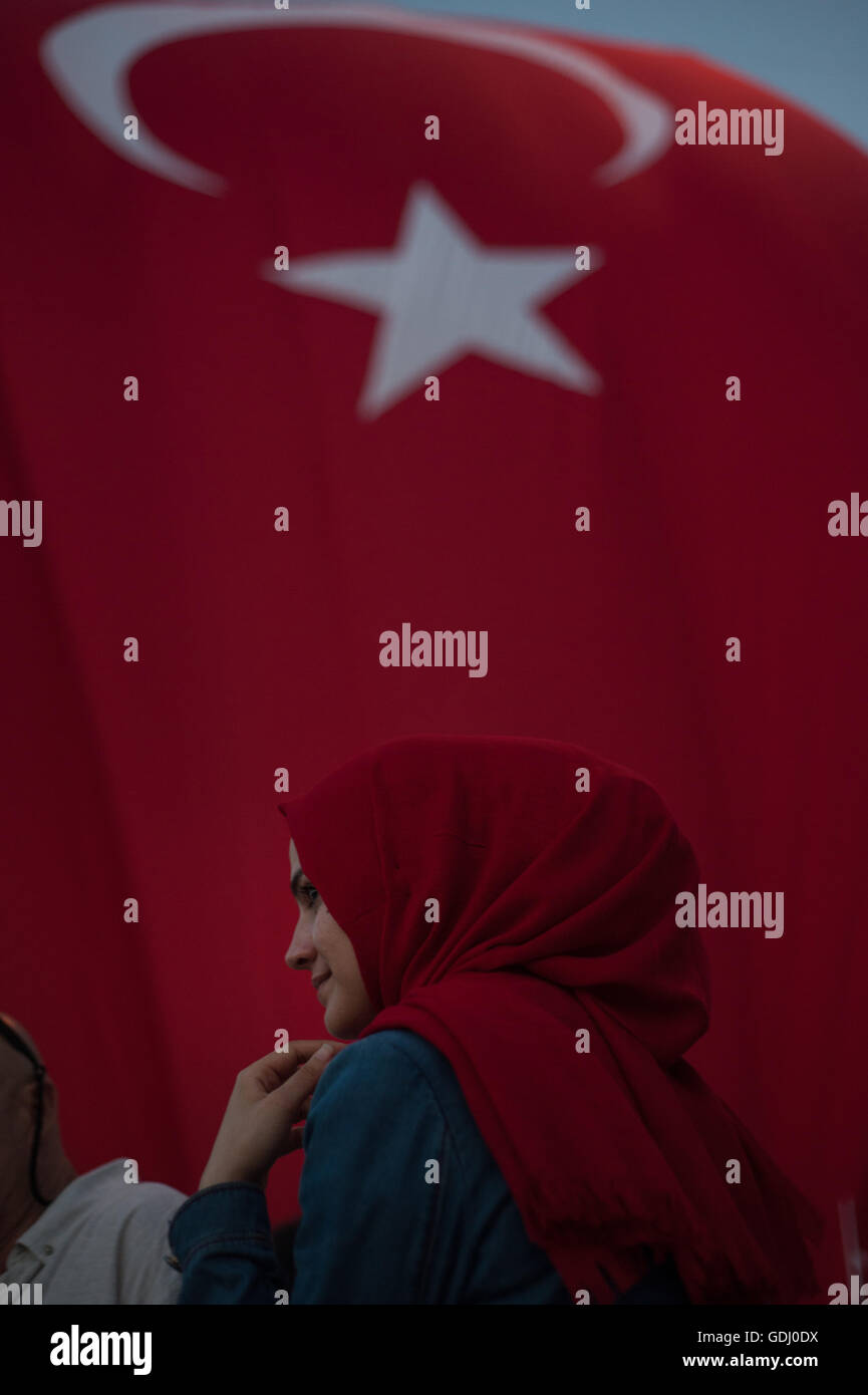Turkish Muslim Woman with red headscarf with Turkish flag behind  attending a pro government rally in Takism Square Istanbul Stock Photo