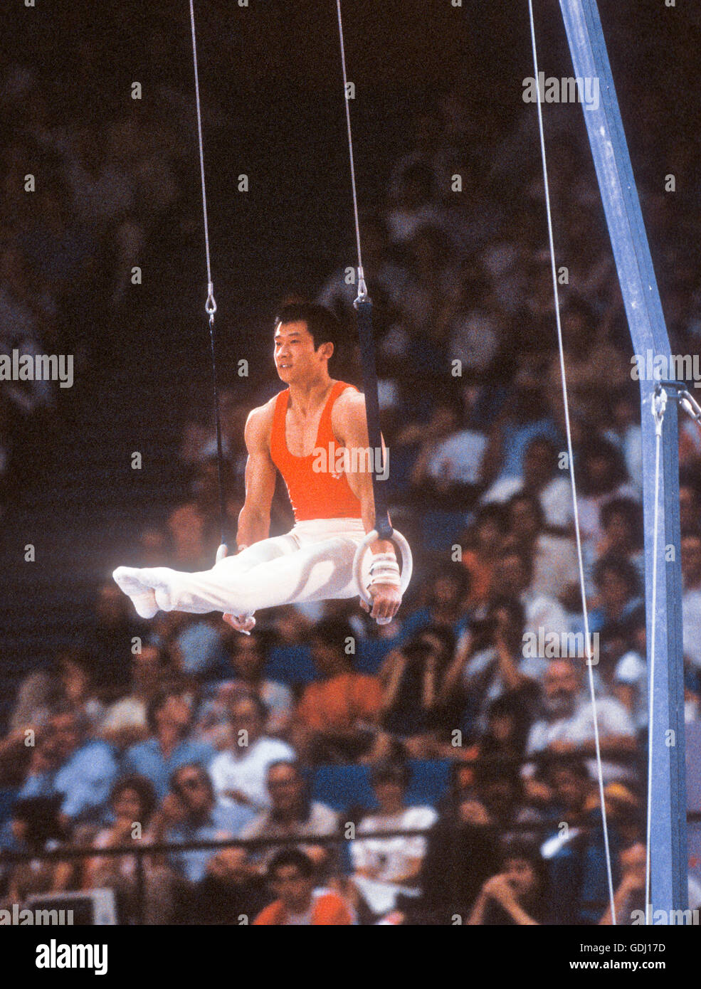Fei Tong of China performs on rings during men's gymnastics competition at 1984 Olympic Games in Los Angeles. Stock Photo