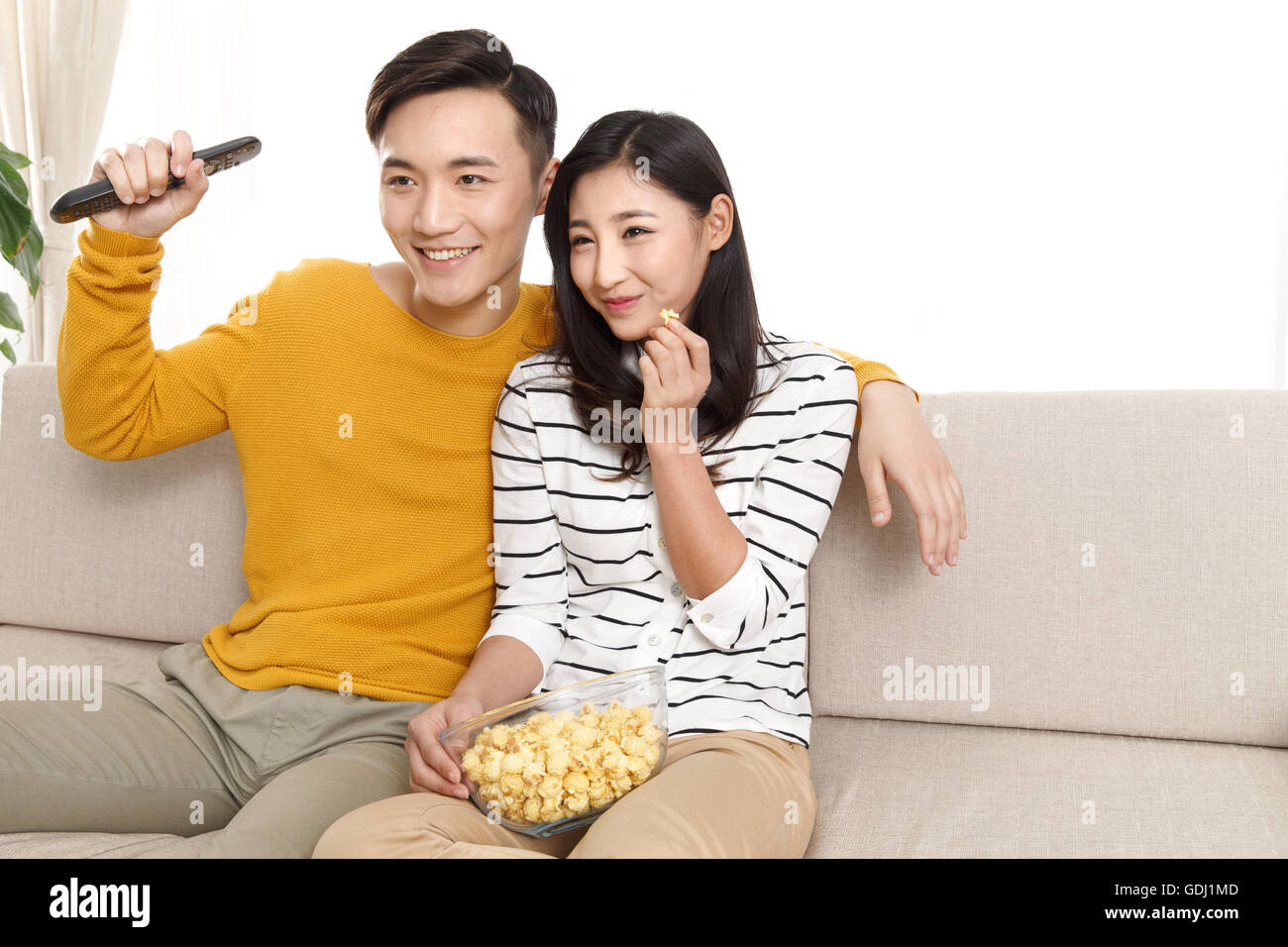 Young couple sitting on the sofa watching TV Stock Photo Alamy
