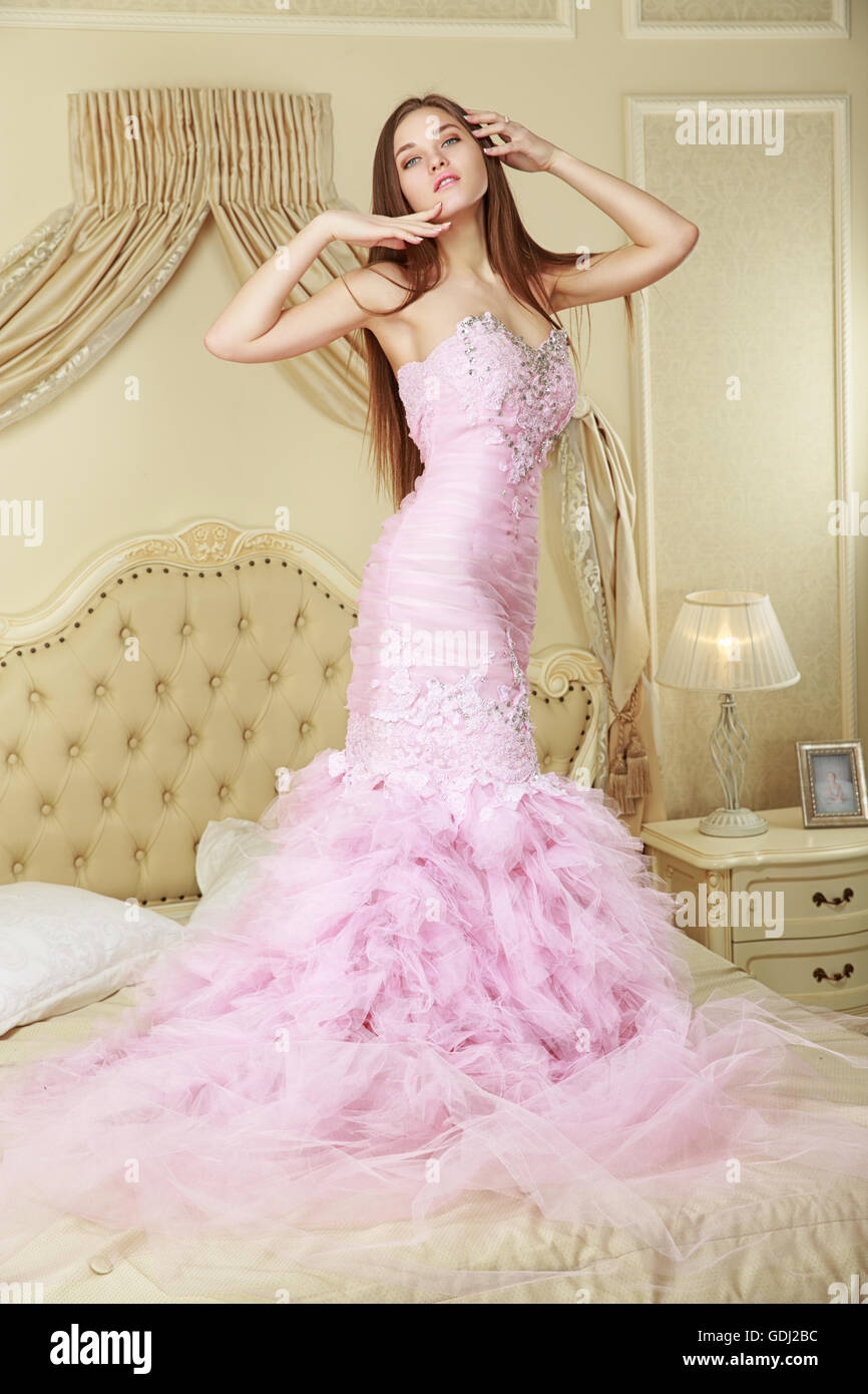 girl in pink wedding dress staying on the bed. Stock Photo