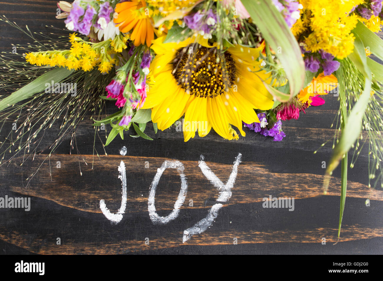 Word Joy with Summer Flowers on a Rustic Wooden Background. Stock Photo