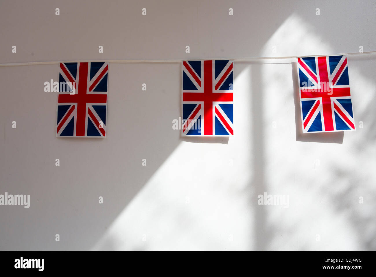 Union Jack flag bunting hanging on an inside white wall Stock Photo Alamy