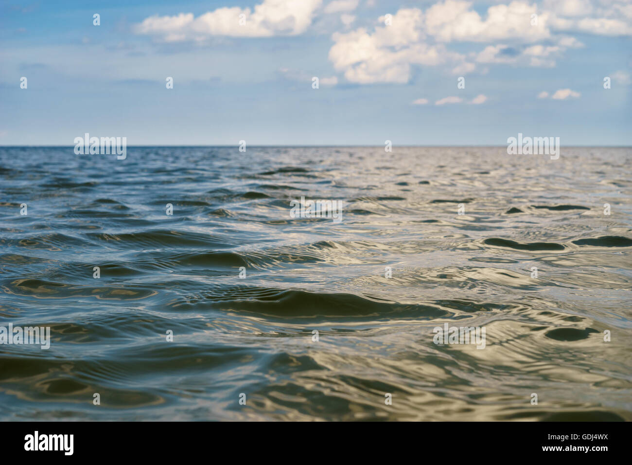 Open sea wavy water surface with cloudy sky on blurred background. Selective focus, low angle view Stock Photo