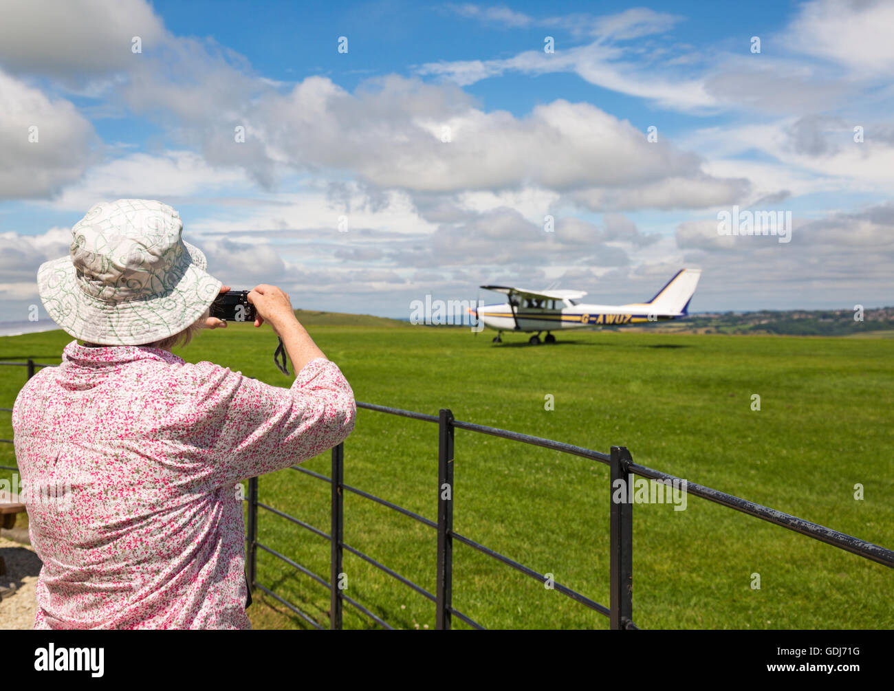 Woman taking photo of light aircraft at Compton Abbas airfield, Dorset in July Stock Photo