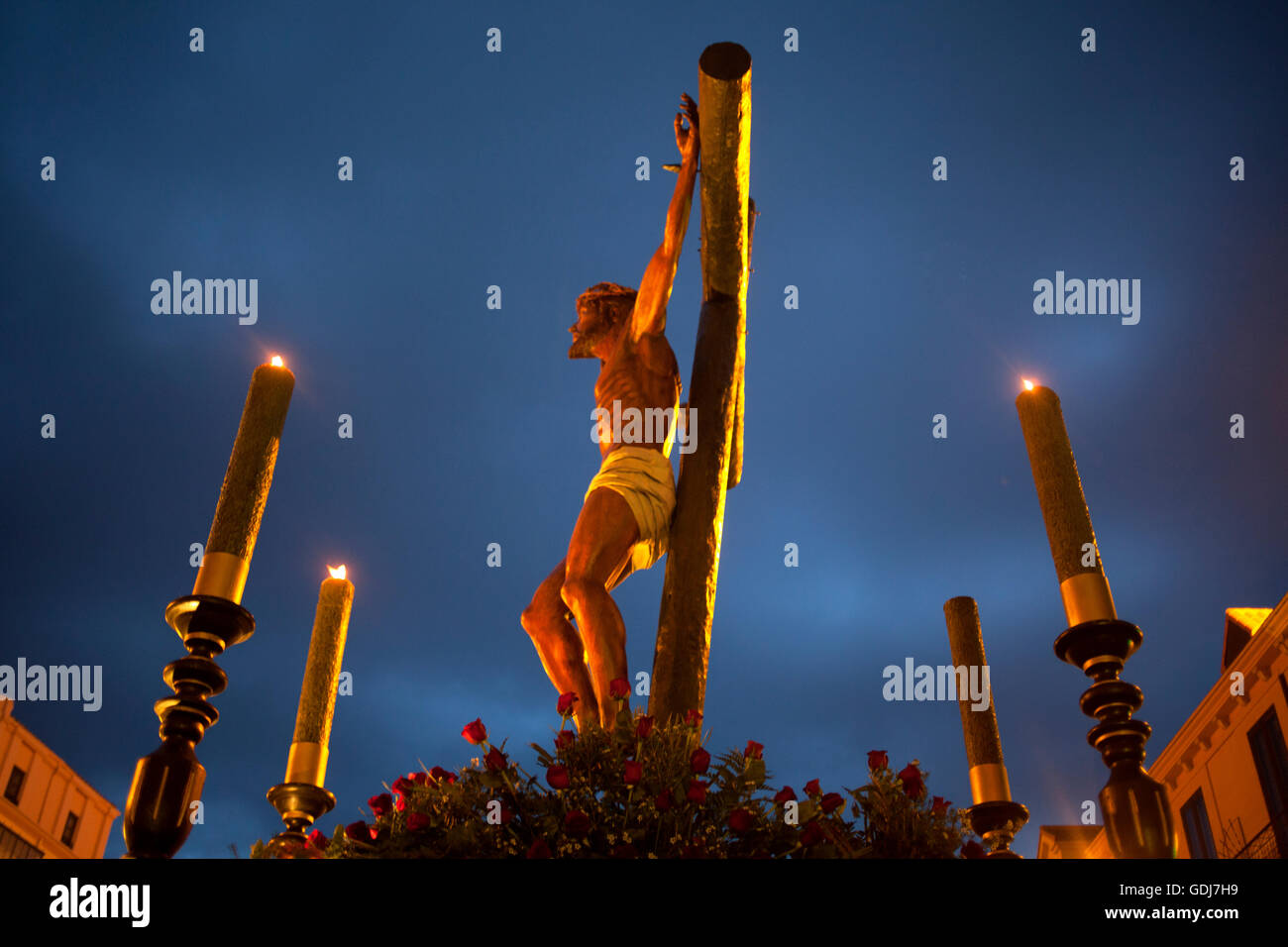 An Image Of Jesus Christ Crucified Decorated With Four Candles During Easter Holy Week Procession