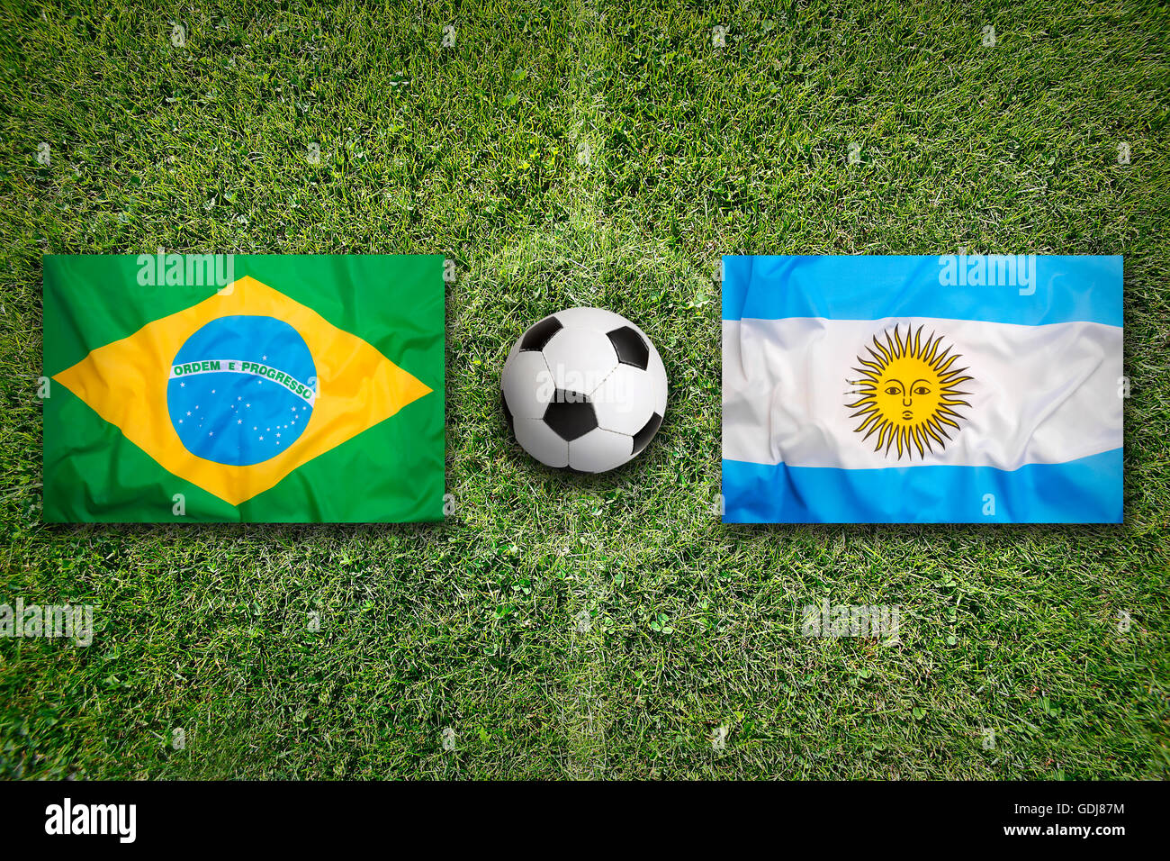 Brazil vs. Argentina flags on green soccer field Stock Photo
