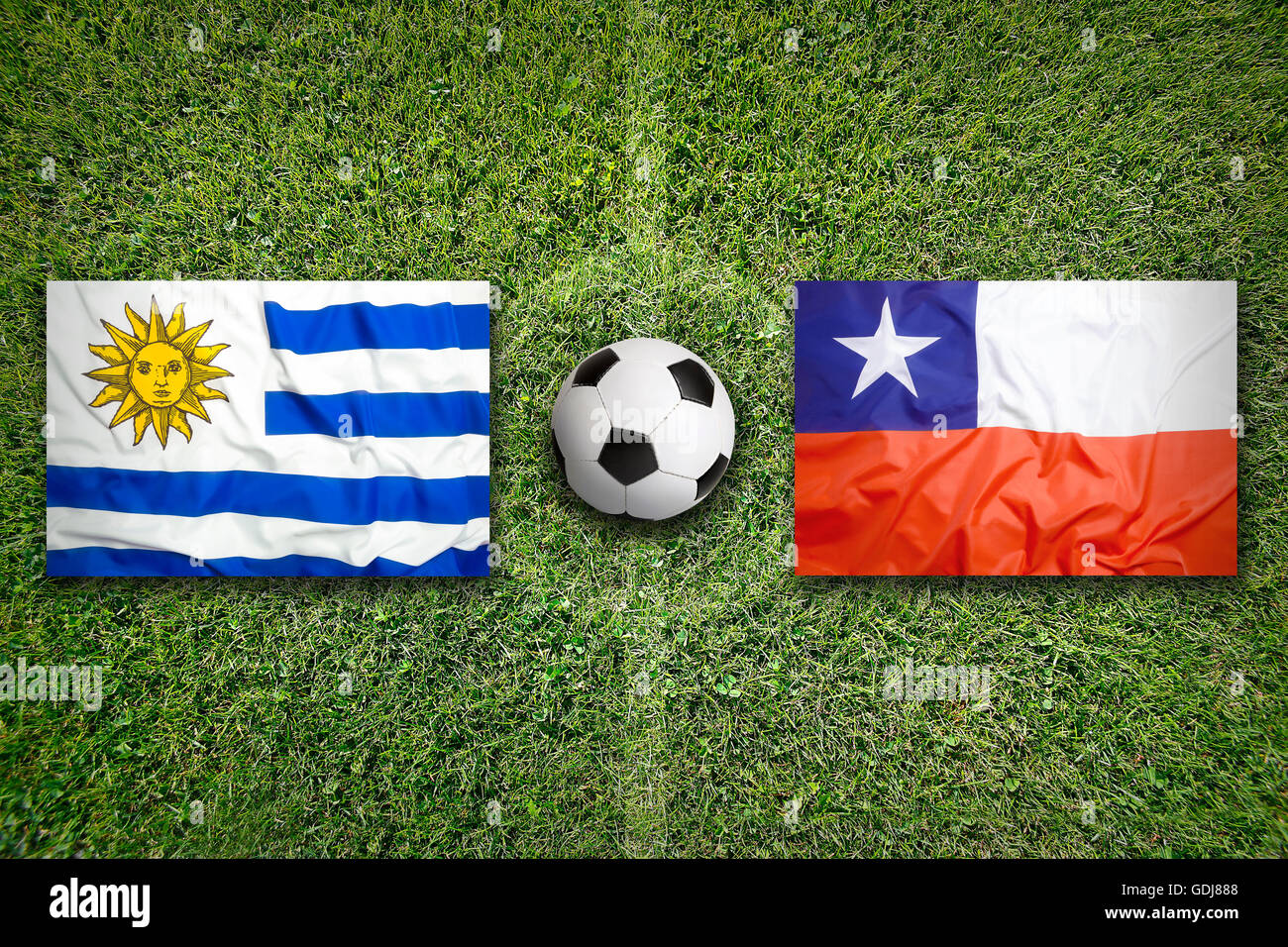 Uruguay vs. Chile flags on green soccer field Stock Photo