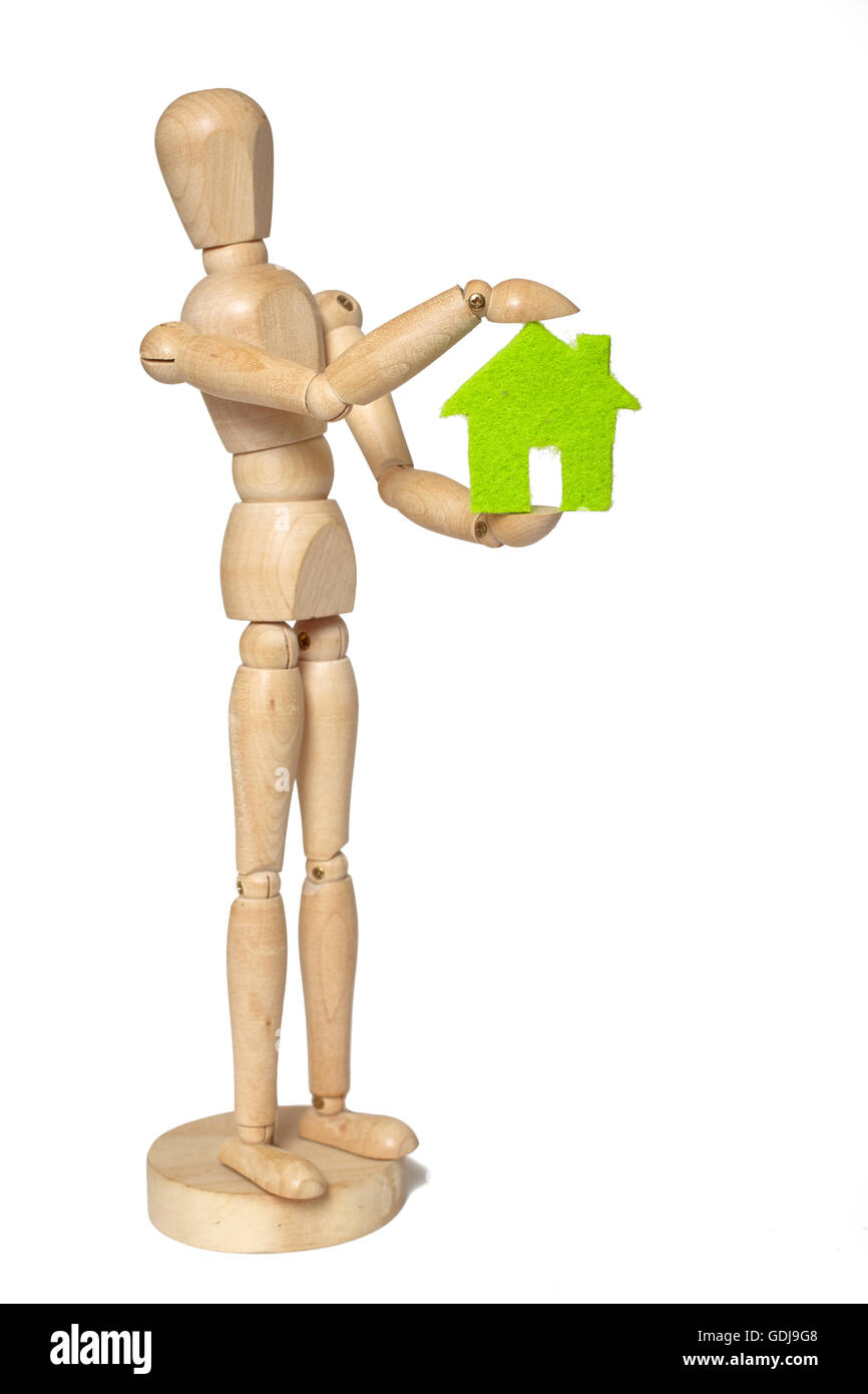 Wooden puppet holds small green house on white background Stock Photo