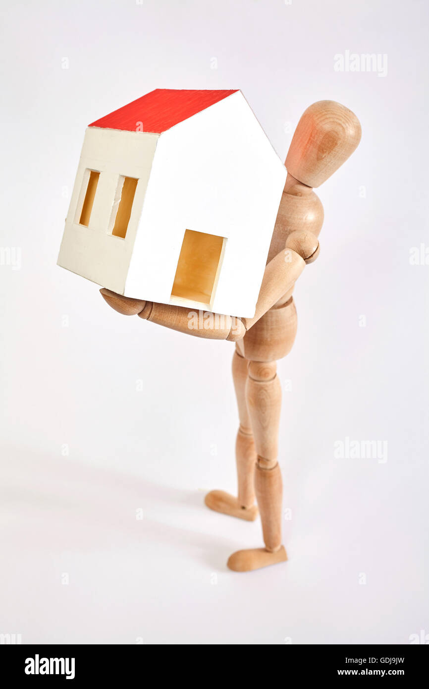 Dummy carrying small house on white background Stock Photo