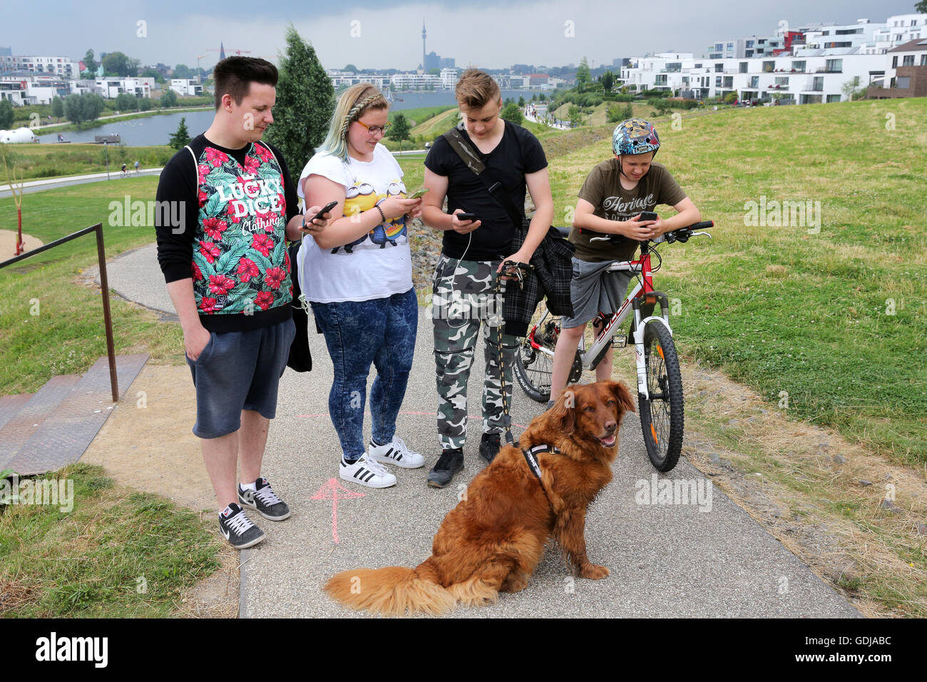POKEMON GO, young people play the new Nintendo game Pokémon go on their smartphones on Lake Phoenix in Dortmund, Germany. The players try to catch in the real world virtual Pokemon monsters on to their smartphone devices. Stock Photo