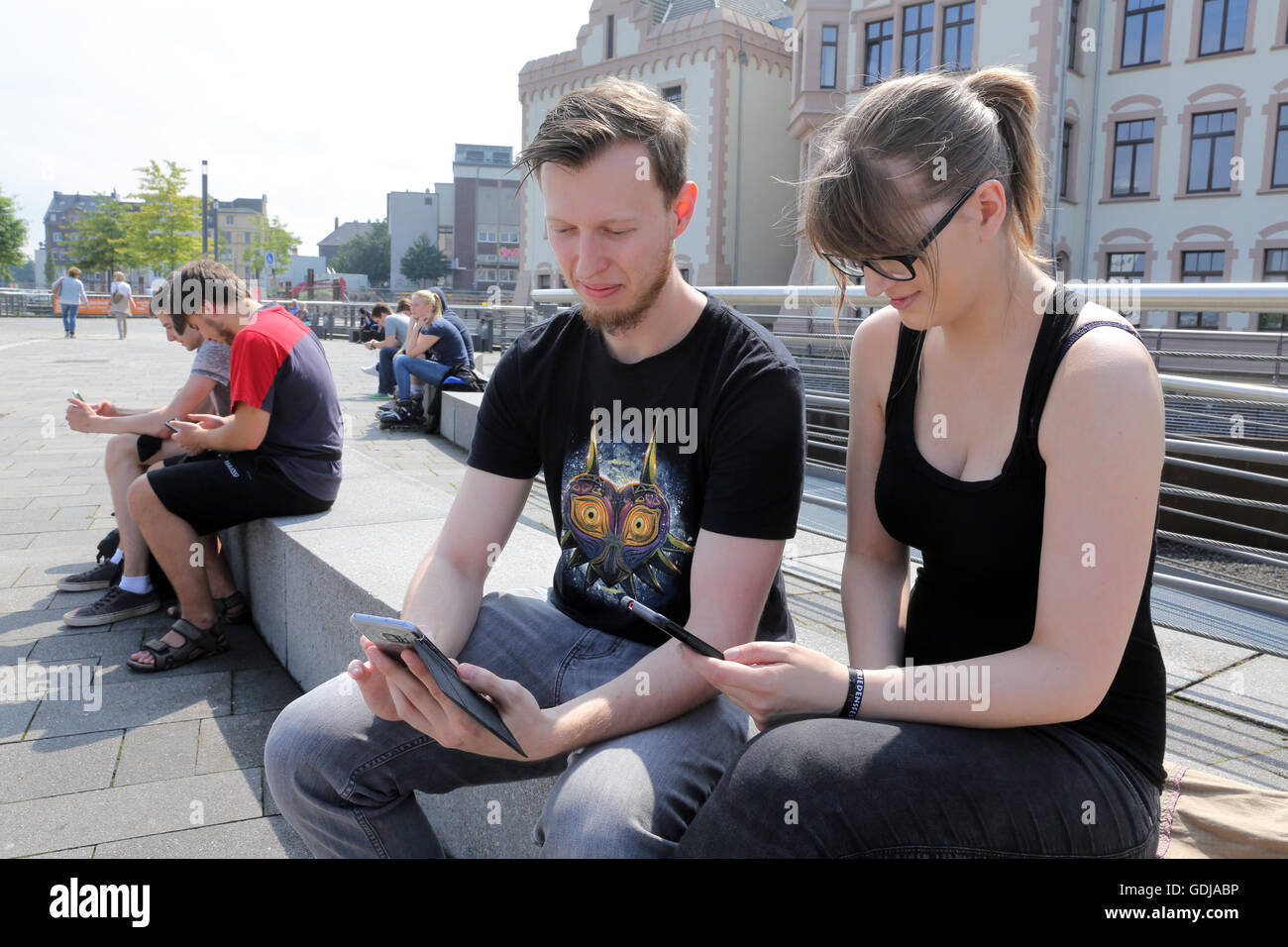 POKEMON GO, young people play the new Nintendo game Pokémon go on their smartphones on Lake Phoenix in Dortmund, Germany. The players try to catch in the real world virtual Pokemon monsters on to their smartphone devices. Stock Photo