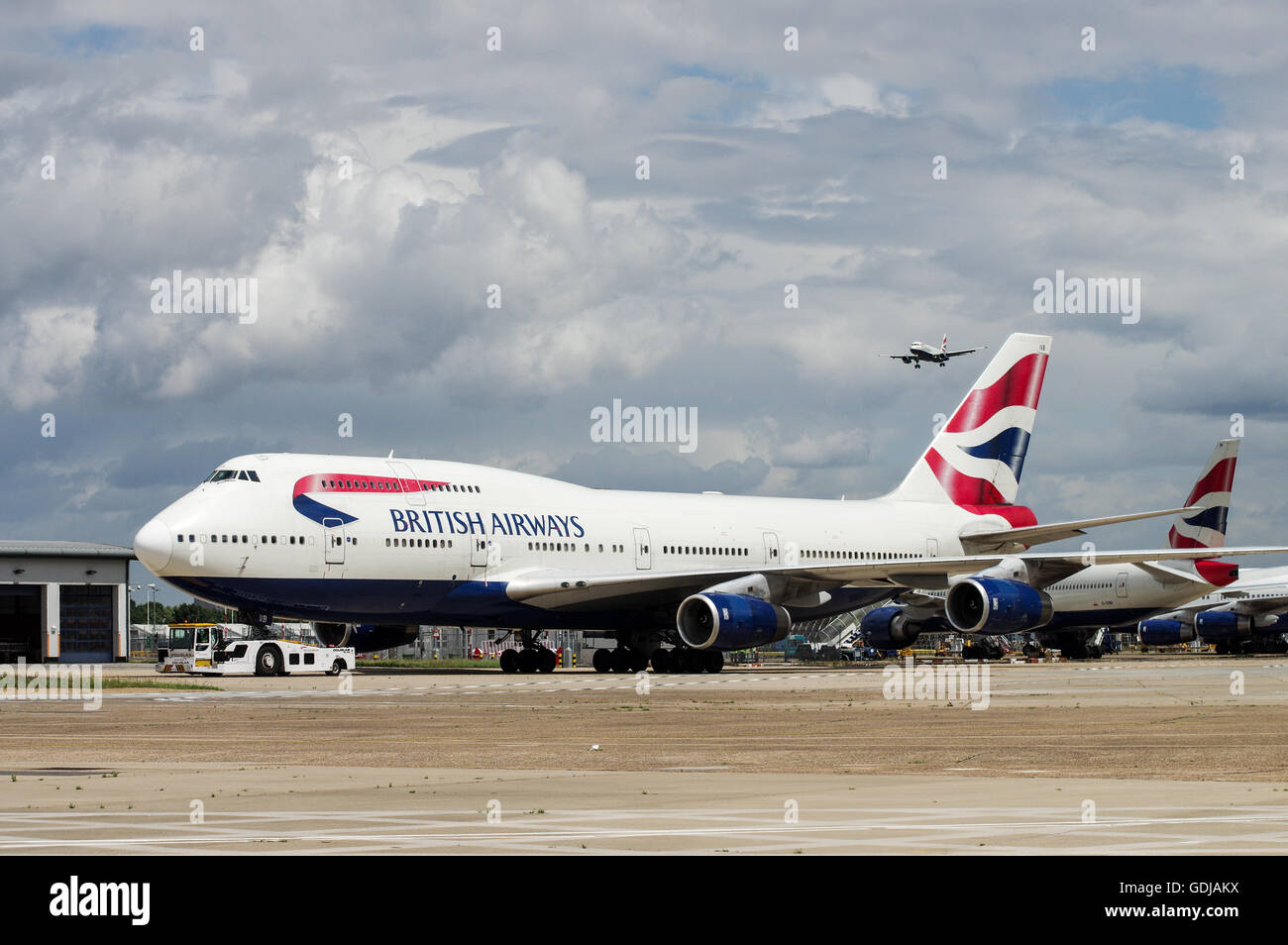 Row of British Airways airplanes with another aircraft approaching in the background at London Heathrow Airport Stock Photo