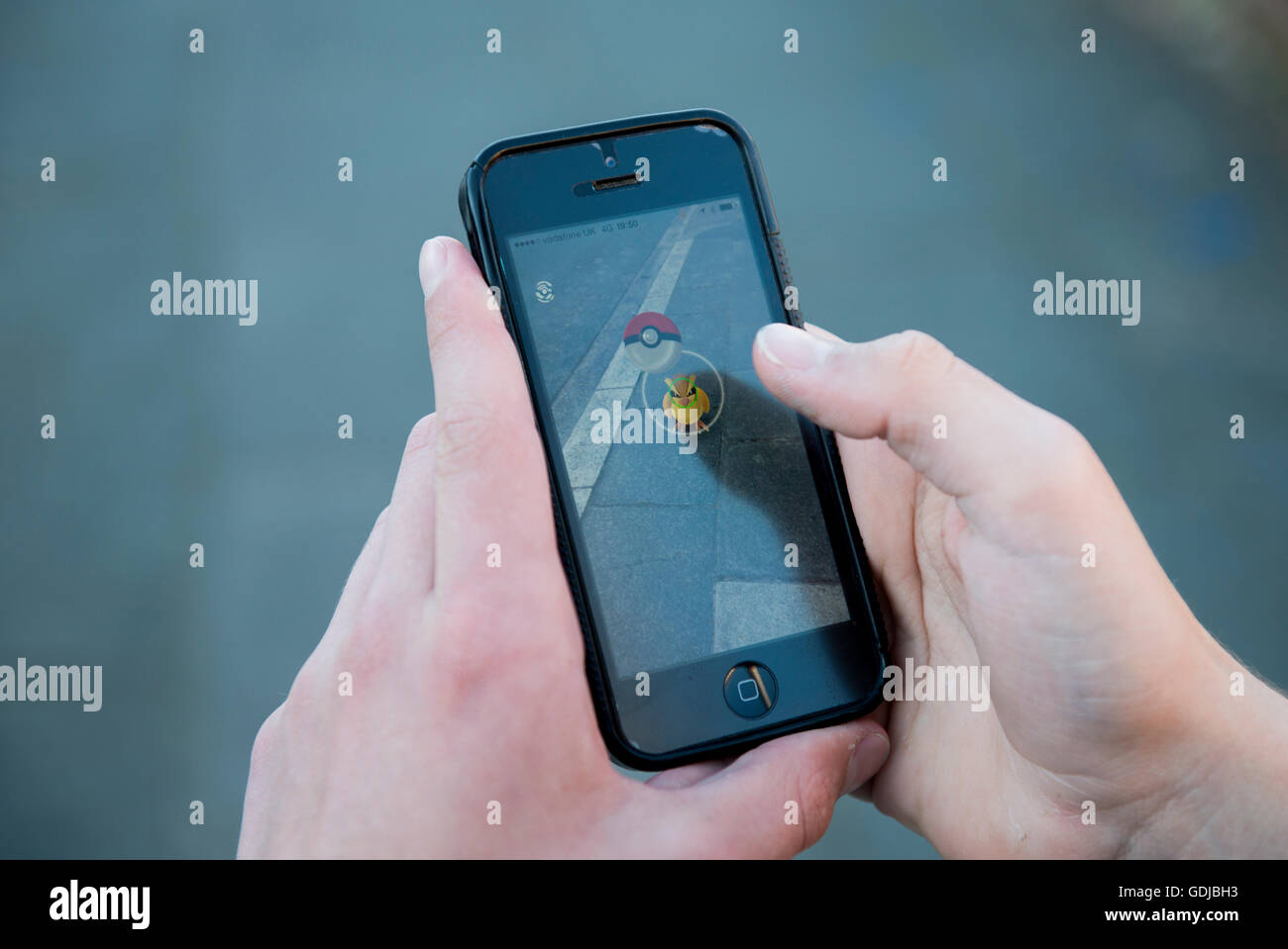 Teenager using an iPhone and playing augmented reality game Pokemon Go Stock Photo