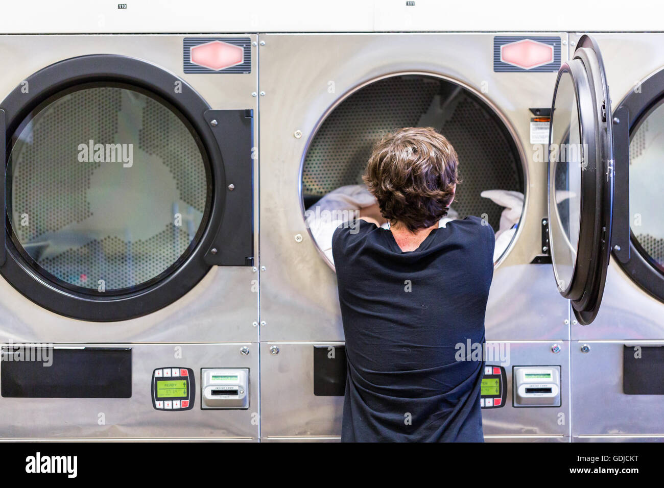 Teenage boy doing the laundry in a public laundromat Stock Photo Alamy