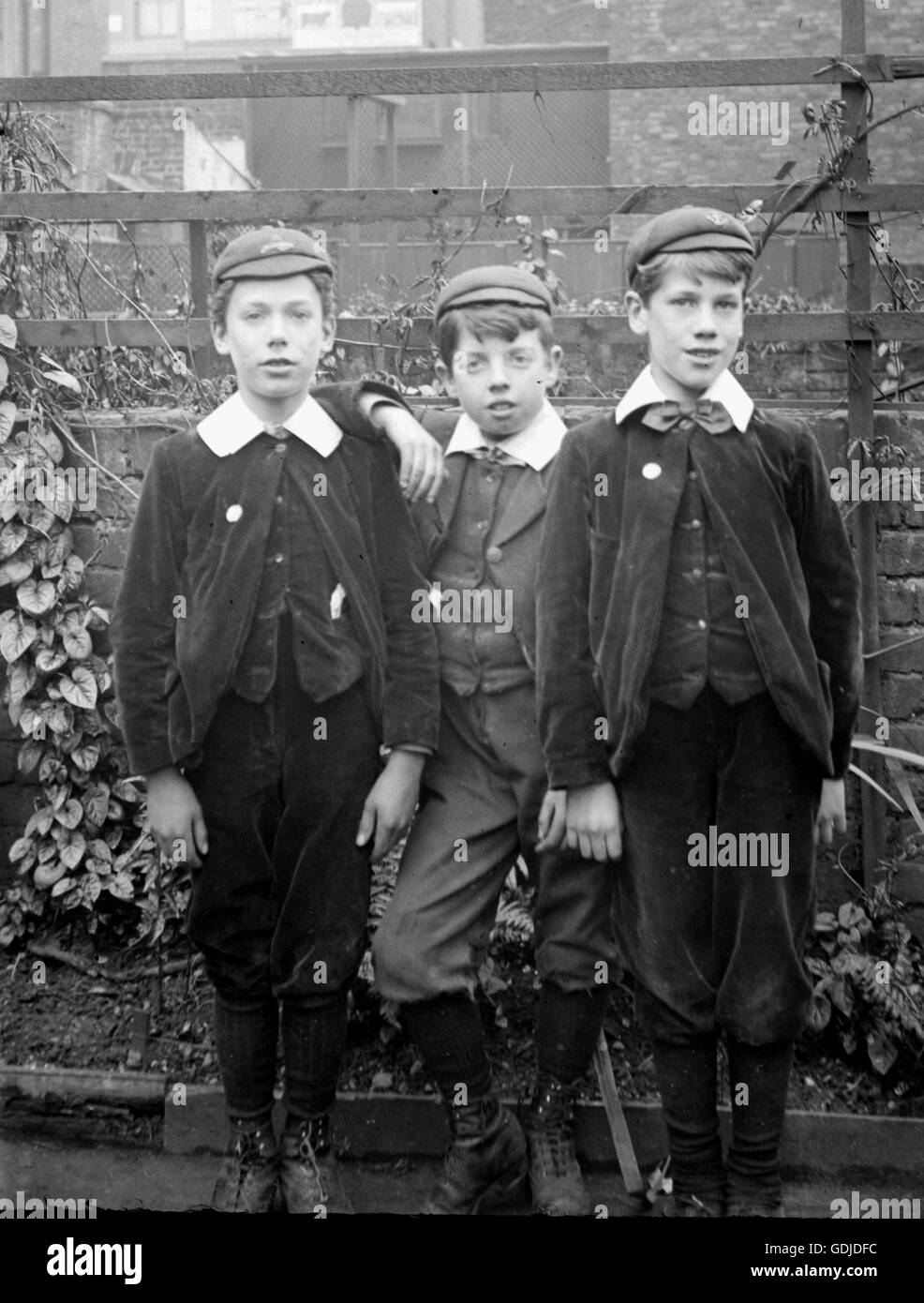 Three boys pose in caps, jackets and trousers. C1910. Photograph by Tony Henshaw Stock Photo
