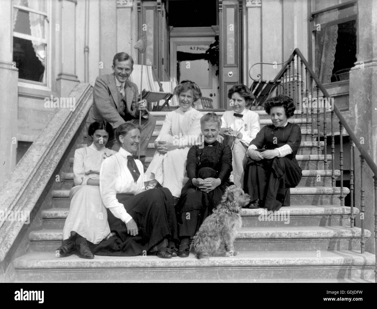 Edwardian post-Victorian era UK with a more informal group photograph of what could be house owners plus staff smiling for the camera or a guest house owner and staff. Note the indifferent terrier dog!  Photo by Tony Henshaw Stock Photo