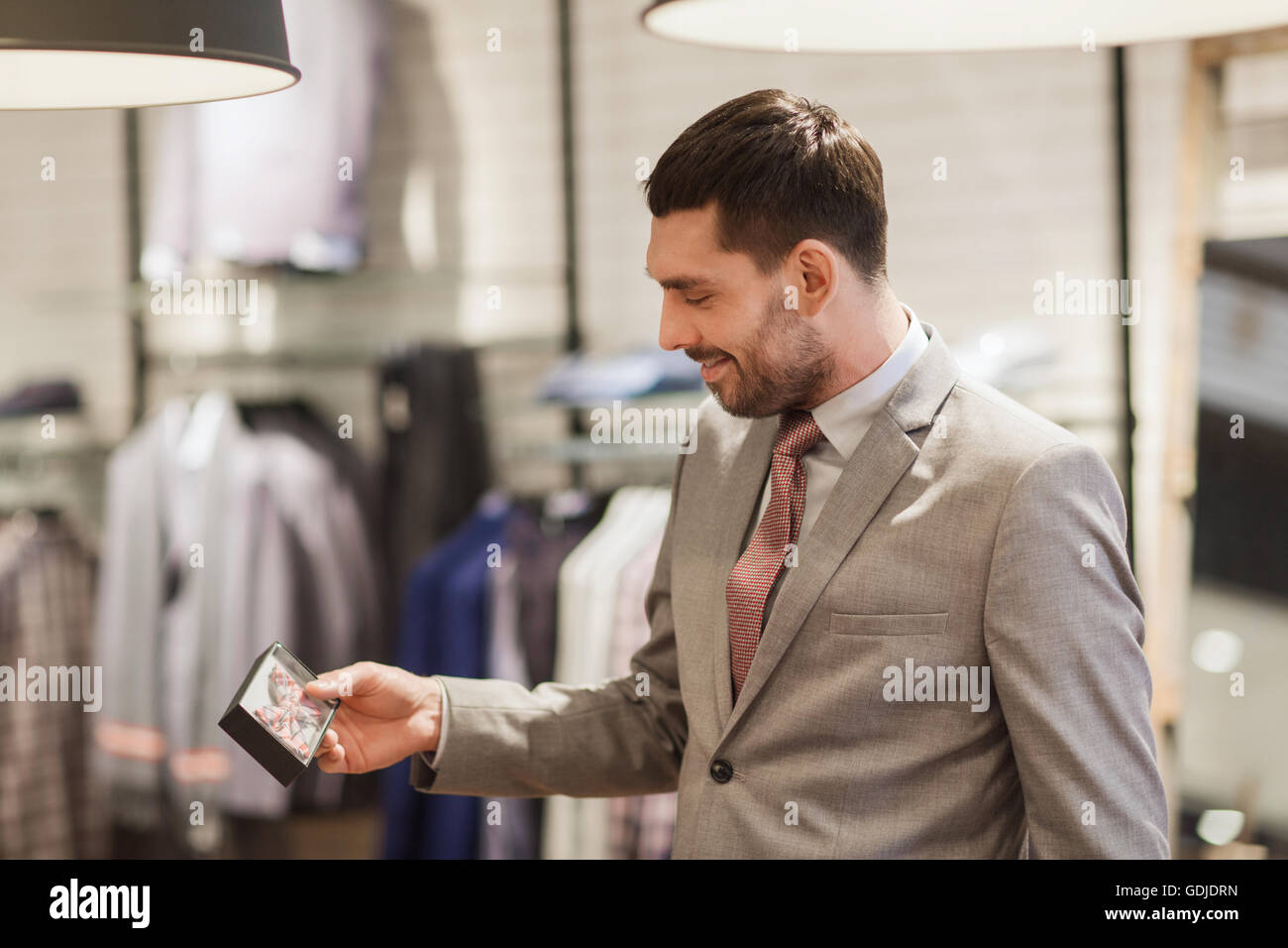 happy young man choosing bow-tie in clothing store Stock Photo - Alamy