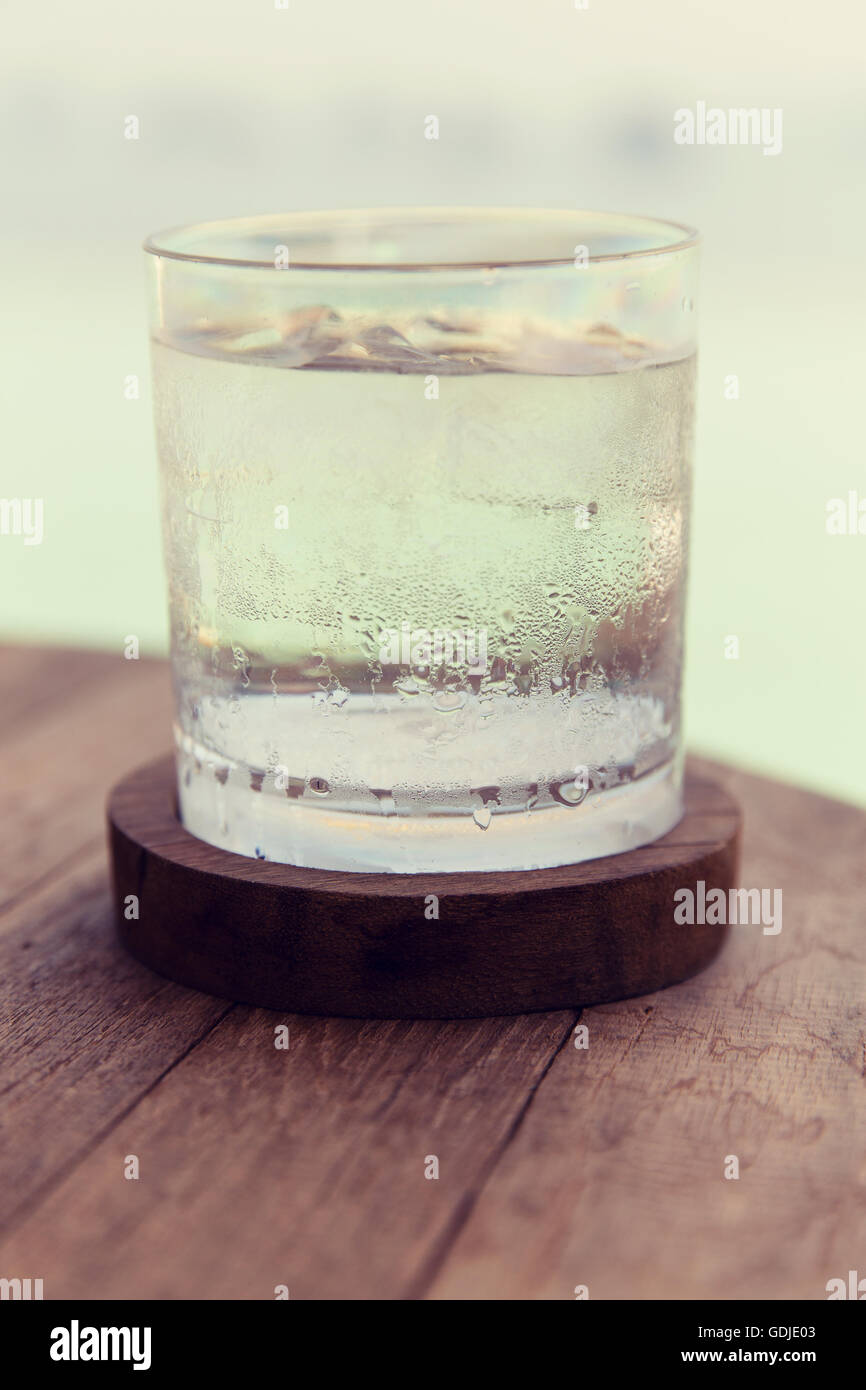 glass of water with ice cubes on table at beach Stock Photo