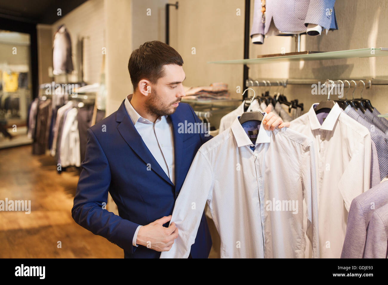 happy young man choosing shirt in clothing store Stock Photo - Alamy