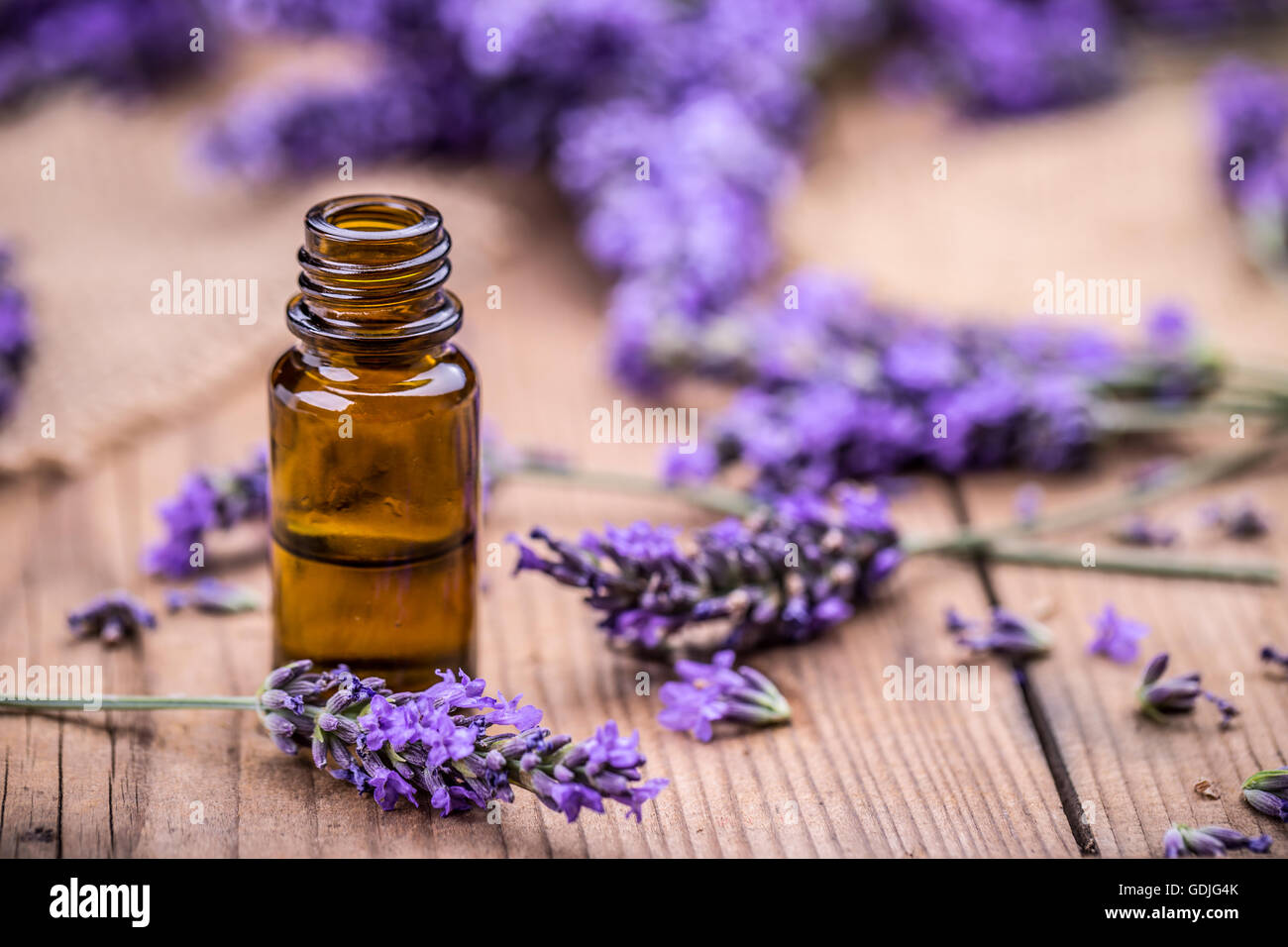 Herbal oil and lavender flowers on wooden background Stock Photo