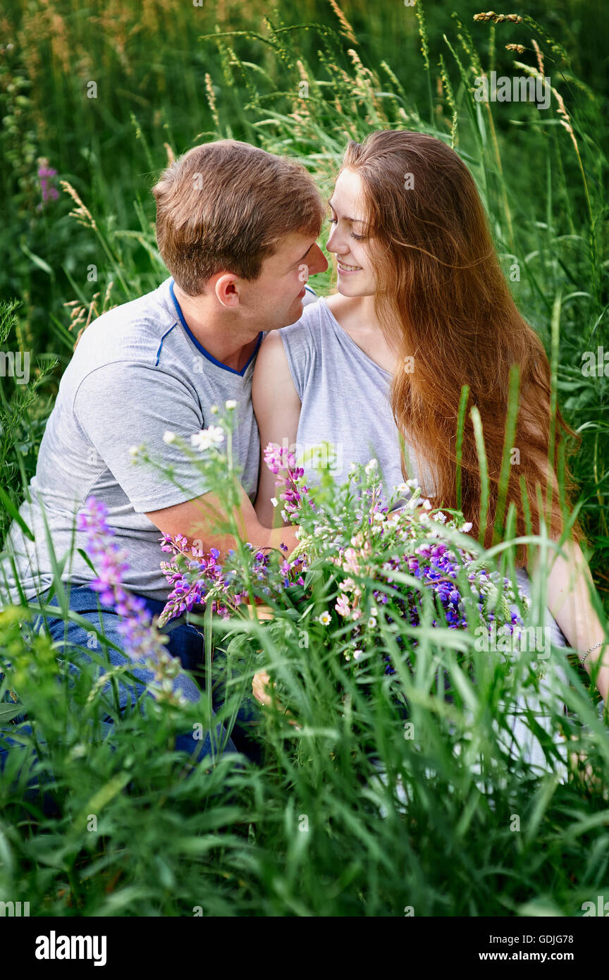 couple in love sitting on green grass summer meadow Stock Photo