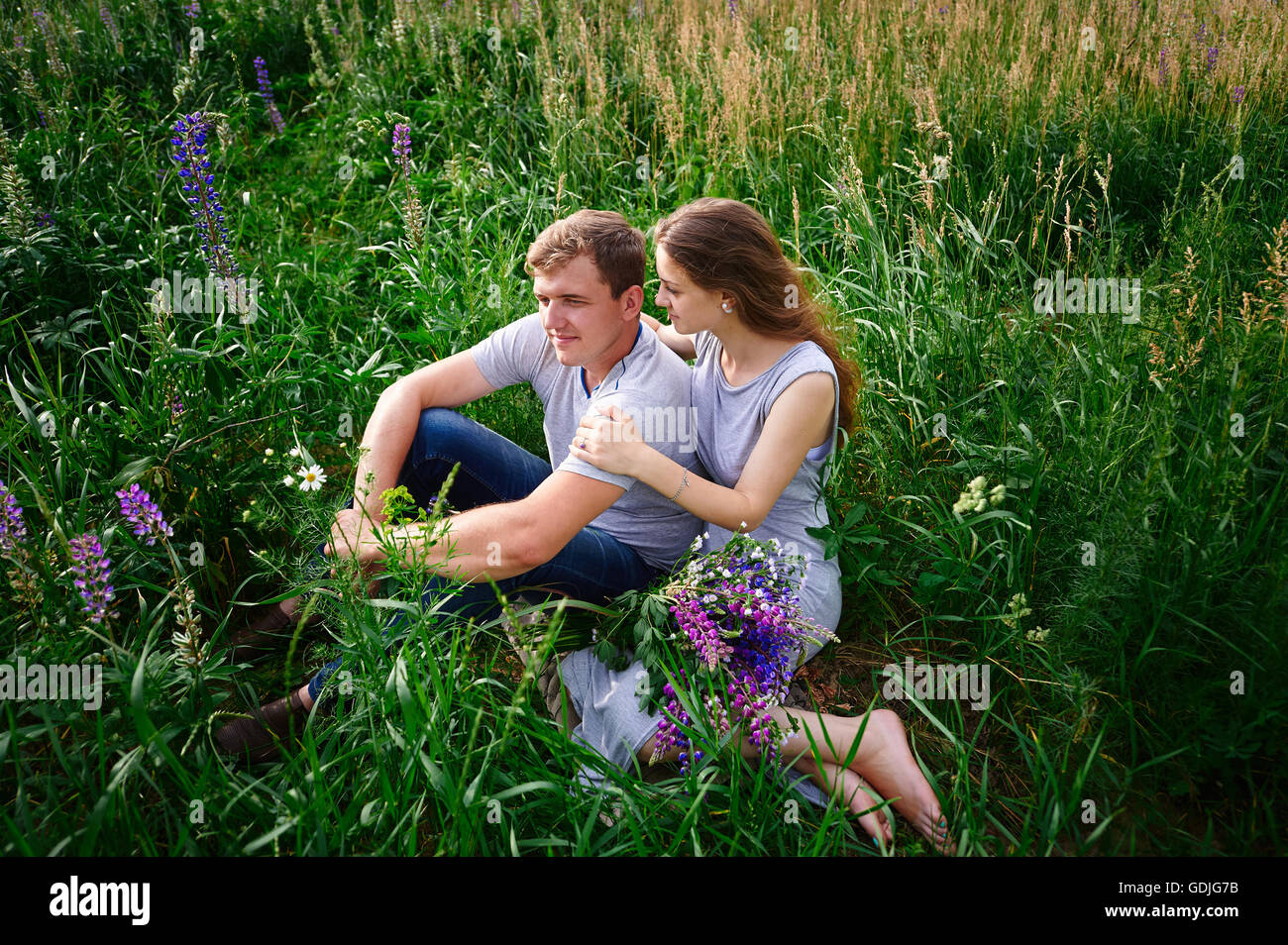 couple in love sitting on green grass summer meadow Stock Photo