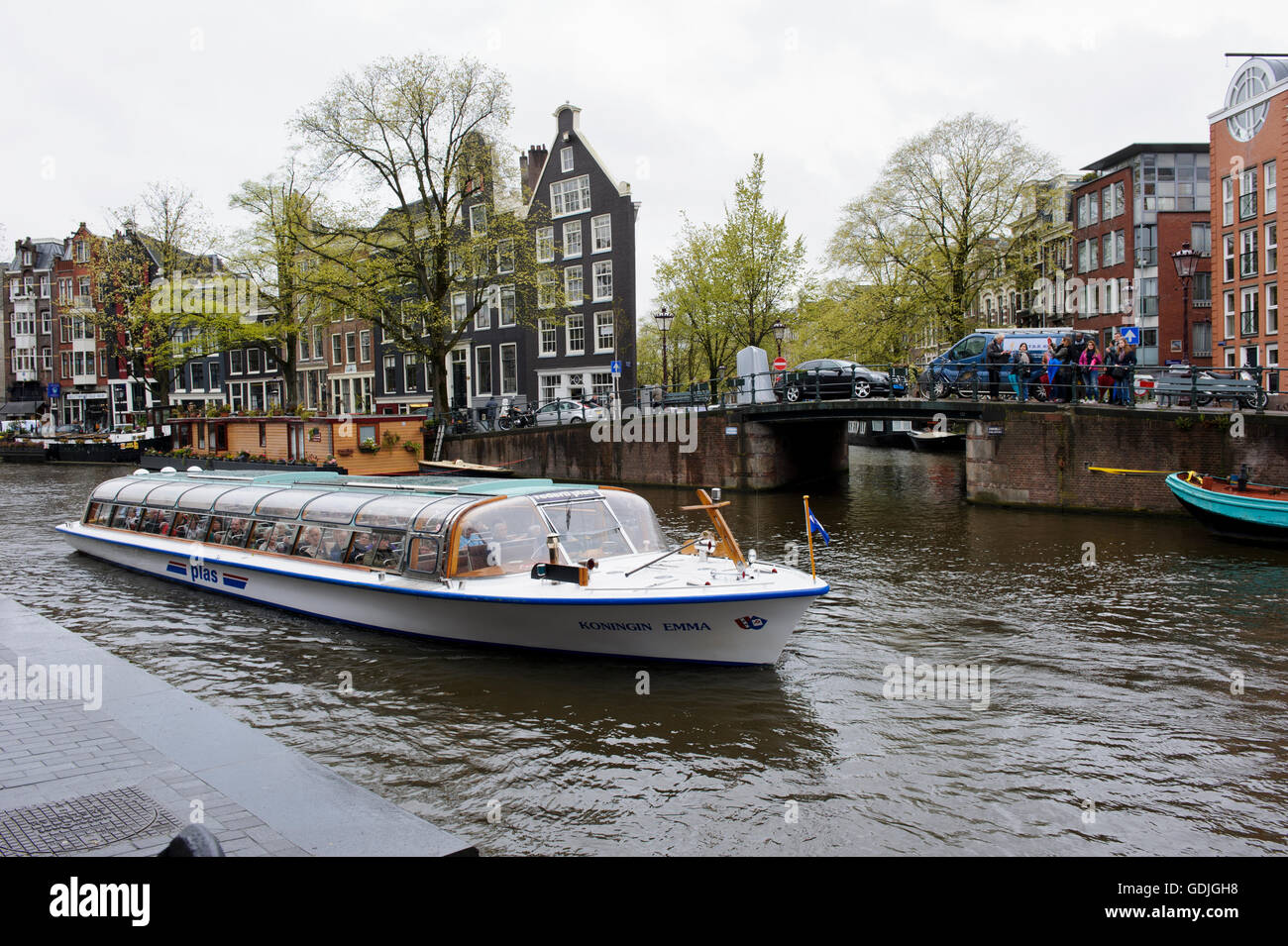 A glass top pleasure boat with tourists moving along the canal in