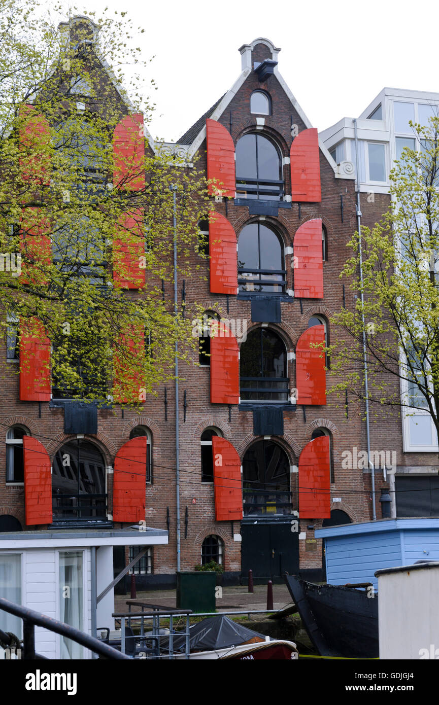 A traditional building with red wooden window shutters in Amsterdam