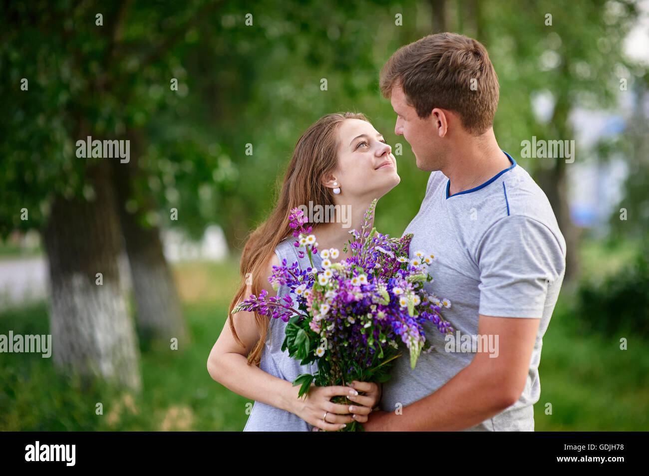 man and woman meet in park with bunch of flowers Stock Photo
