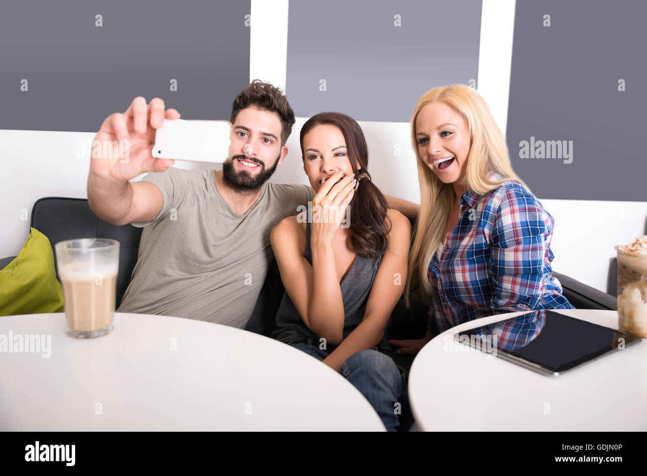 Friends siting at a table and taking a selfie in a coffee shop Stock ...