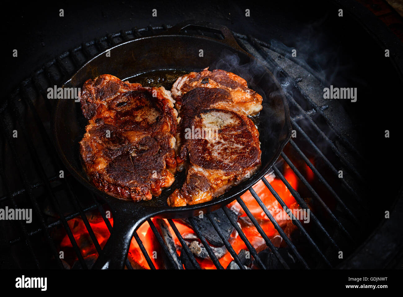 Two nice steaks cooking on the grill in a cast iron skillet Stock Photo