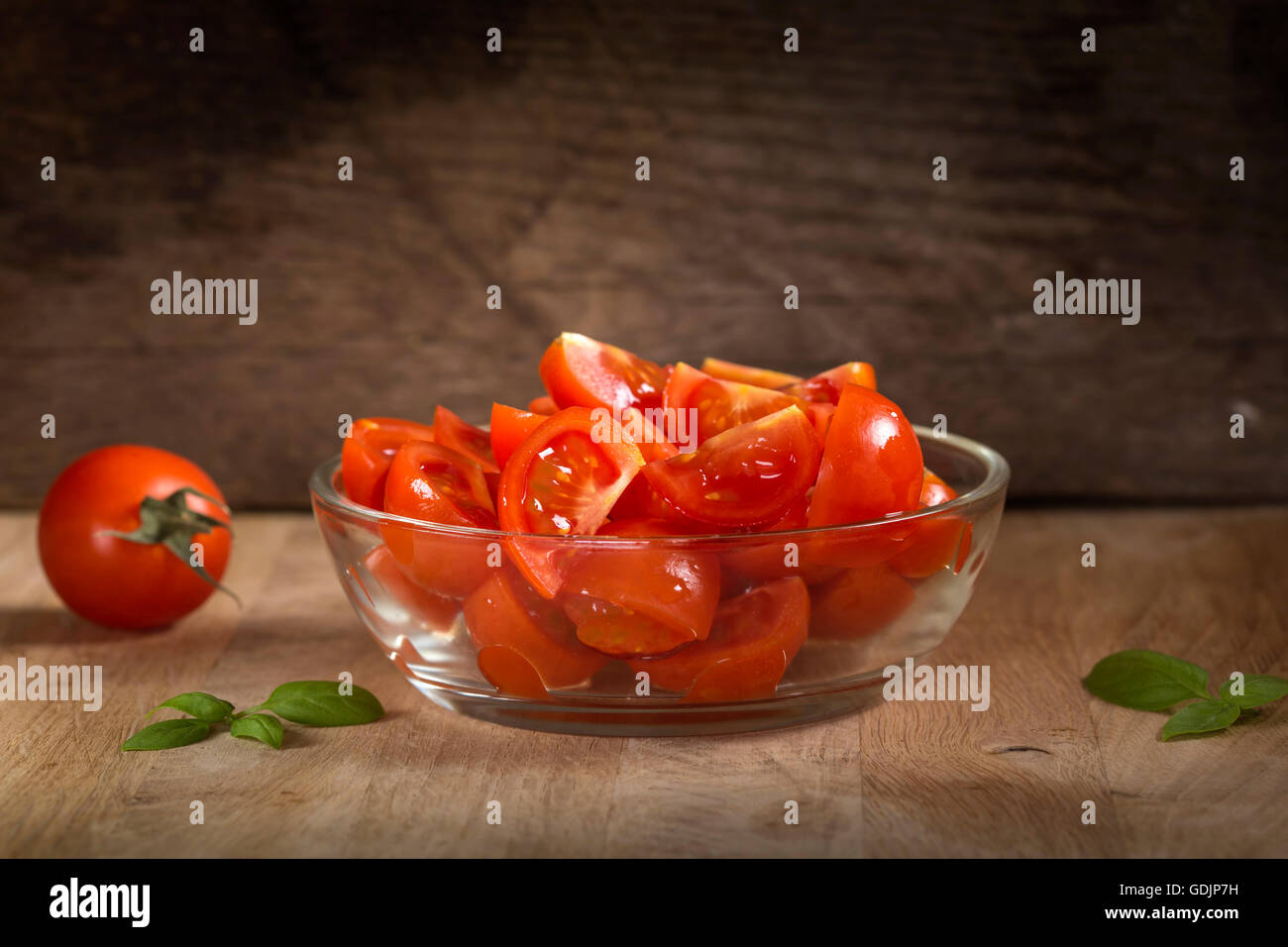 Sliced tomatoes in bowl on old rustic wooden background Stock Photo - Alamy