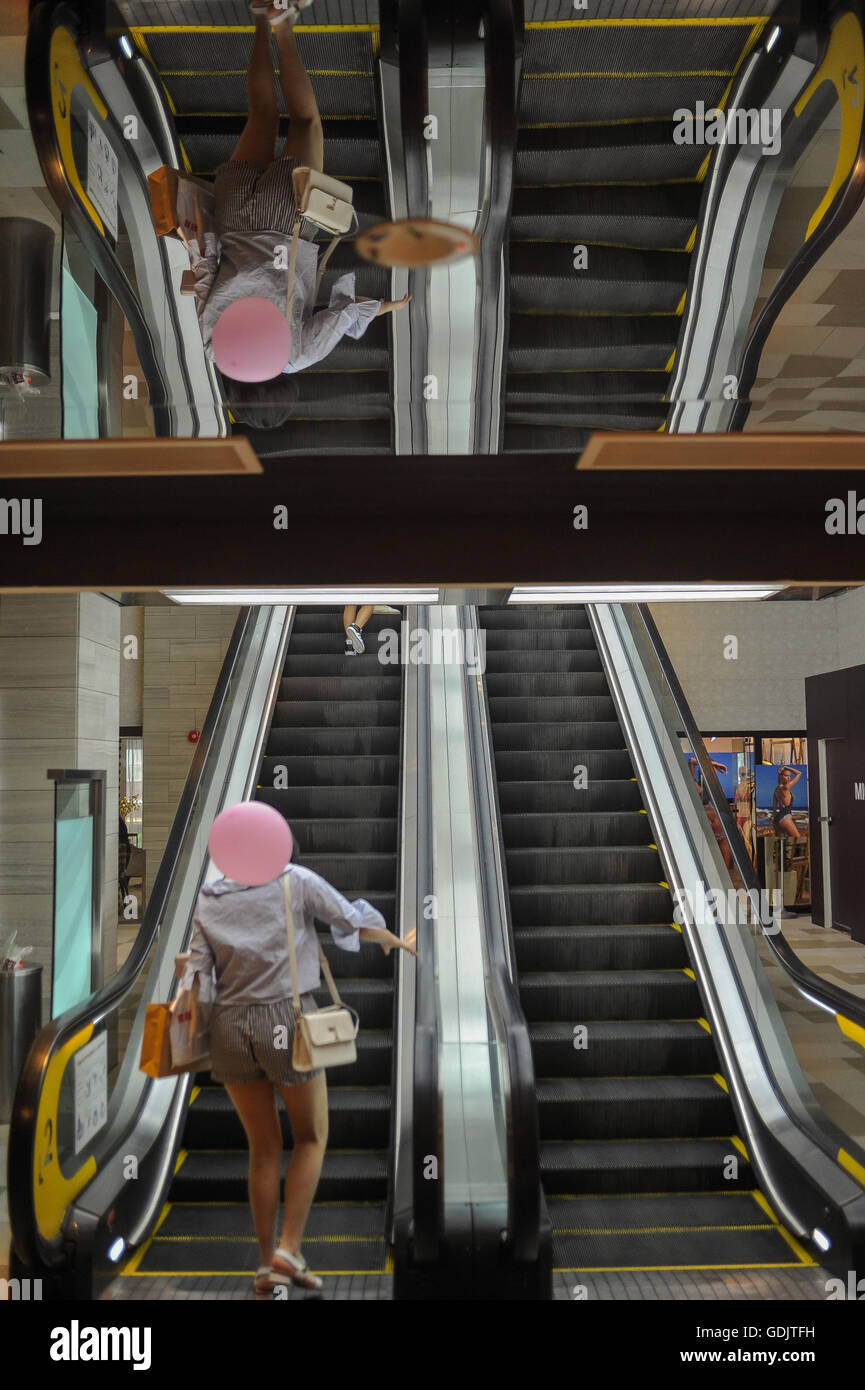 SINGAPORE, July 16, 2016. A woman on an escalator at the Mandarin Orchard Singapore Shopping mall. Stock Photo