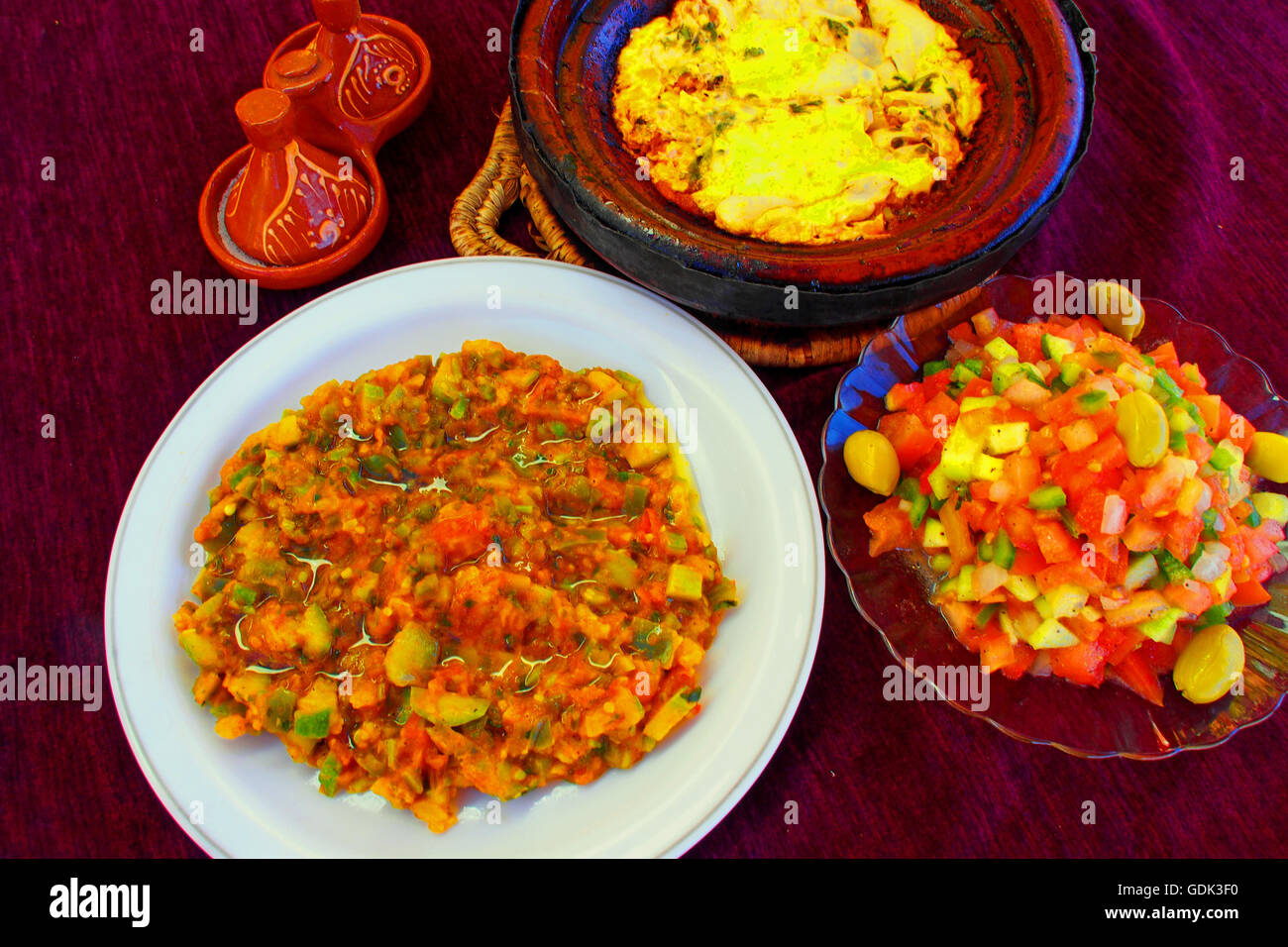 Eggplant salad, and Moroccan salad, with tomatoes greenpepper fruits, onions and coriander, an "Berber" omelette with tomatoes at Agdz, Food, Morocco. Stock Photo