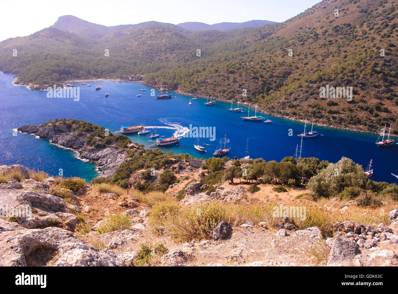 Gulets surround the ancient ruins on Gemiler Island, also known as St Nicholas Island, south of Gocek on the Aegean coast, Turkey. Stock Photo