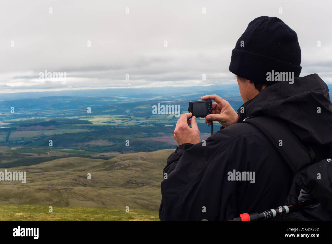 man taking picture of landscape from ben wyvis looking over to dingwall and strathpeffer Stock Photo