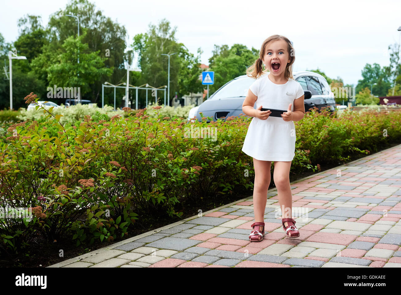 Little girl with a smartphone outdoors Stock Photo