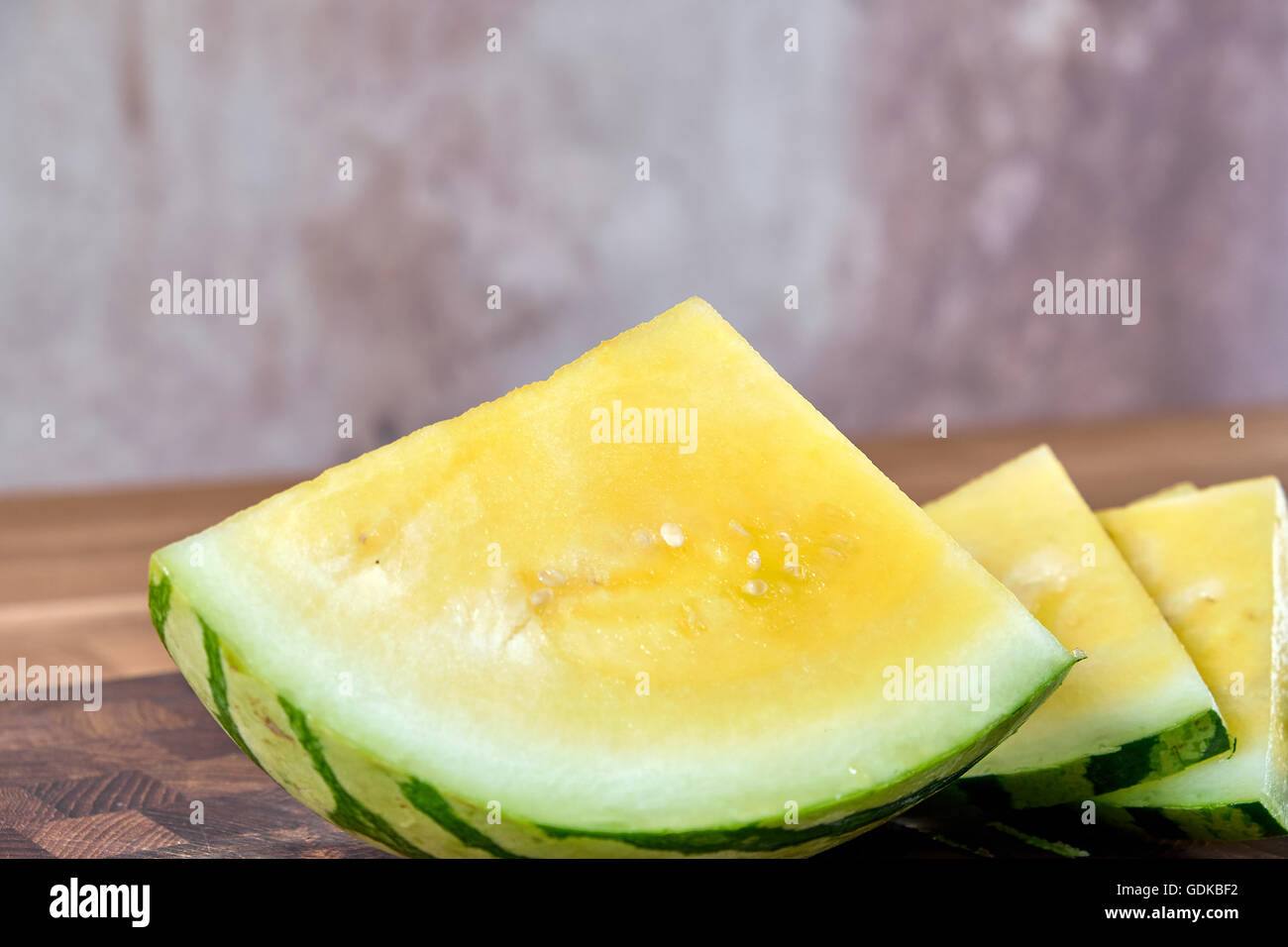 Yellow watermelon slice, lying on a table of dark brown laminated hardwood Stock Photo