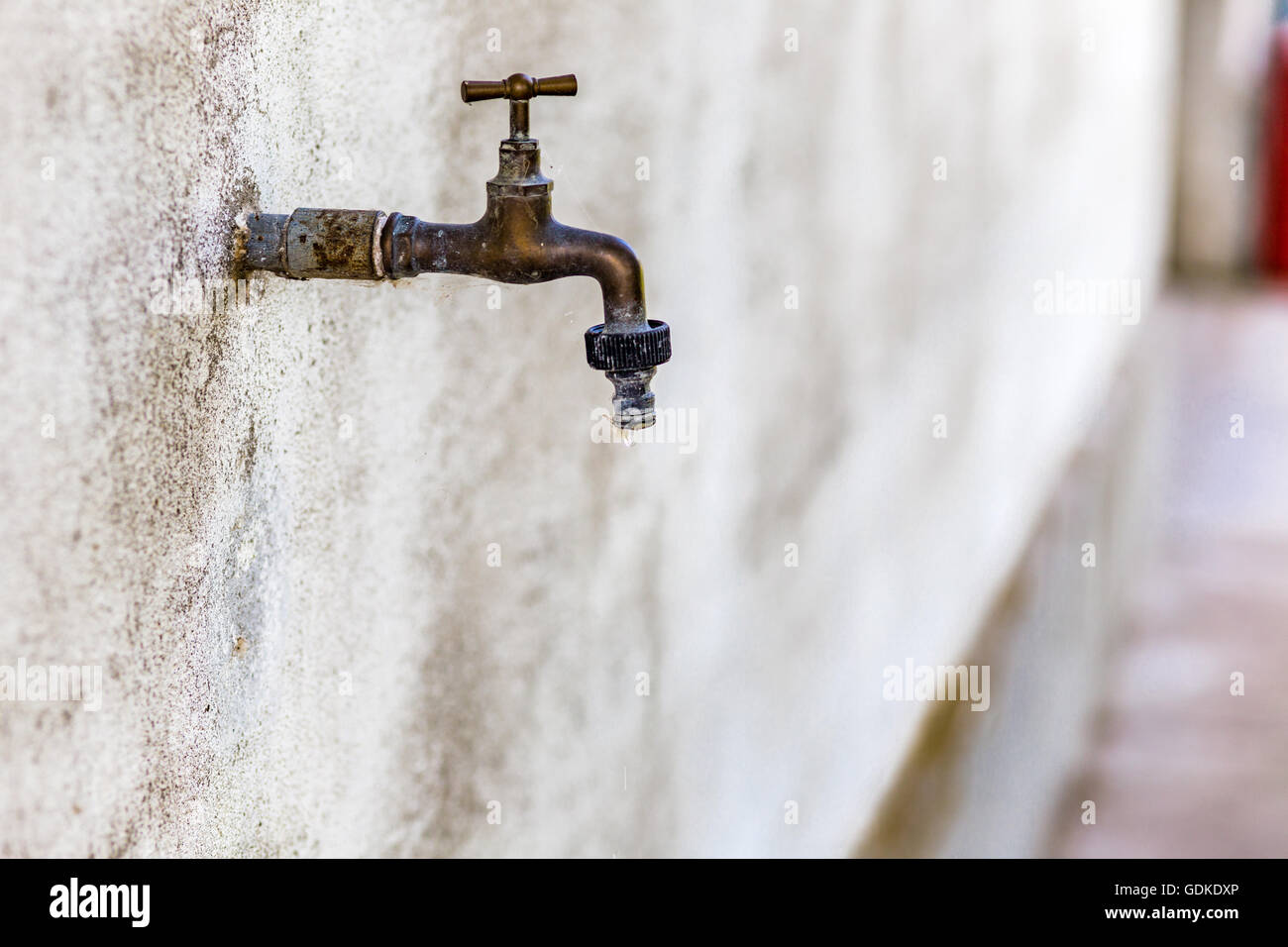 rusty old faucet drips wasting water Stock Photo