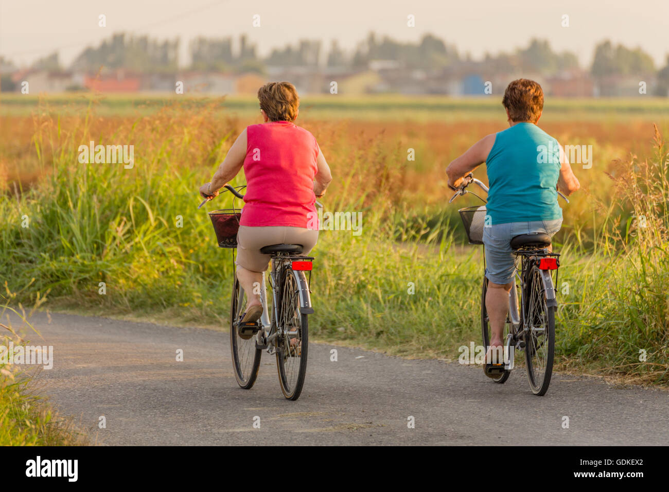 two fat bottom middle-aged women go cycling through the countryside in Italy Stock Photo