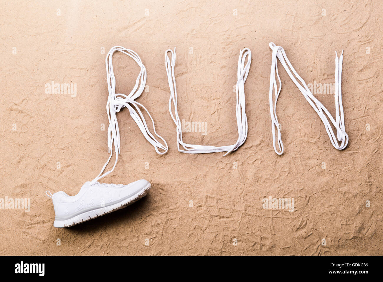 Running shoe and run sign made of shoelaces, sand Stock Photo