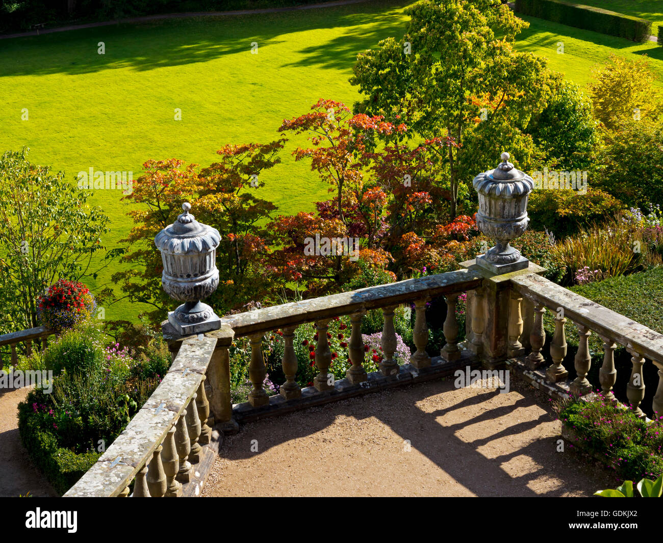 View looking down on stone balustrade with urns in a formal garden with lawn in the background in summer sunshine Stock Photo