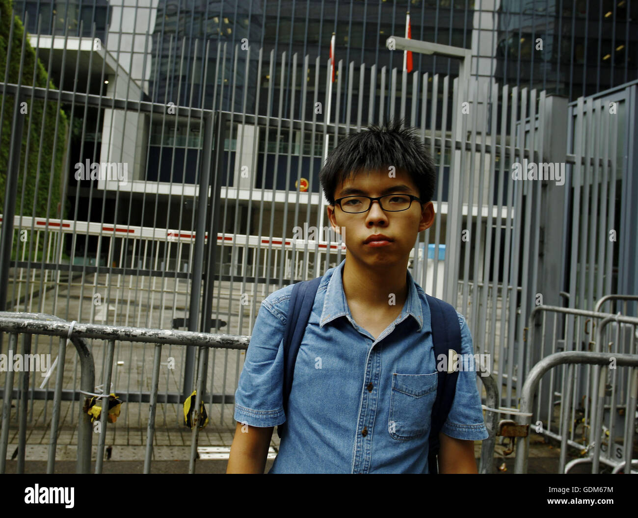 June 16, 2016 - Joshua Wong (19), a former student leader and political activist who led the massive civil disobedience, OCCUPATION CENTRAL-UMBRELLA MOVEMENT in 2014 pose in front of the entrance at Central Government Office. Wong is charged over climbing into the Hong Kong Government complex forecourt known as Civic Square on Sep 26, 2014, which triggered wider rallies that eventually turned into full scale clash with police authority two days later when police fired tear gas to disperse crowds. Wongs verdict set for July 21, 2016, over charges of taking part in an unlawful assembly and incit Stock Photo