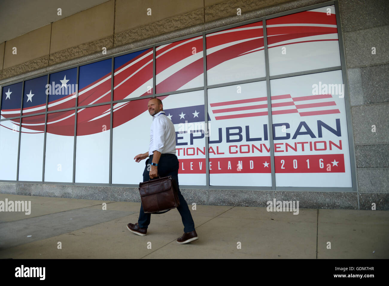 Cleveland, USA. 18th July, 2016. A man walks past the poster outside Quicken Loans Arena where the Republican National Convention is held in Cleveland, Ohio, the United States, July 18, 2016. © Yin Bogu/Xinhua/Alamy Live News Stock Photo